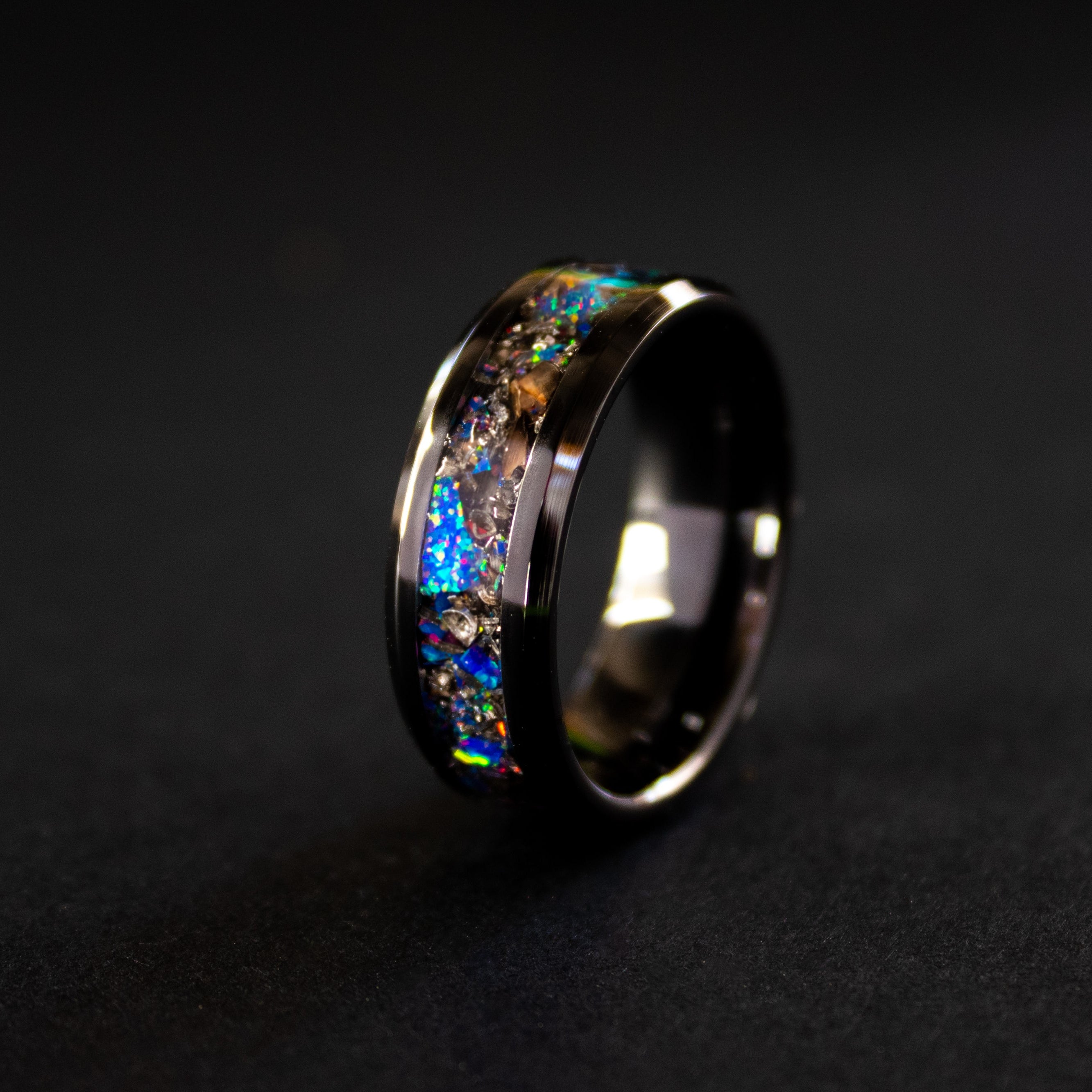 Close up of genuine T-Rex fossil and Campo del Cielo meteorite shavings suspended in midnight opal inlay on beveled black ceramic ring