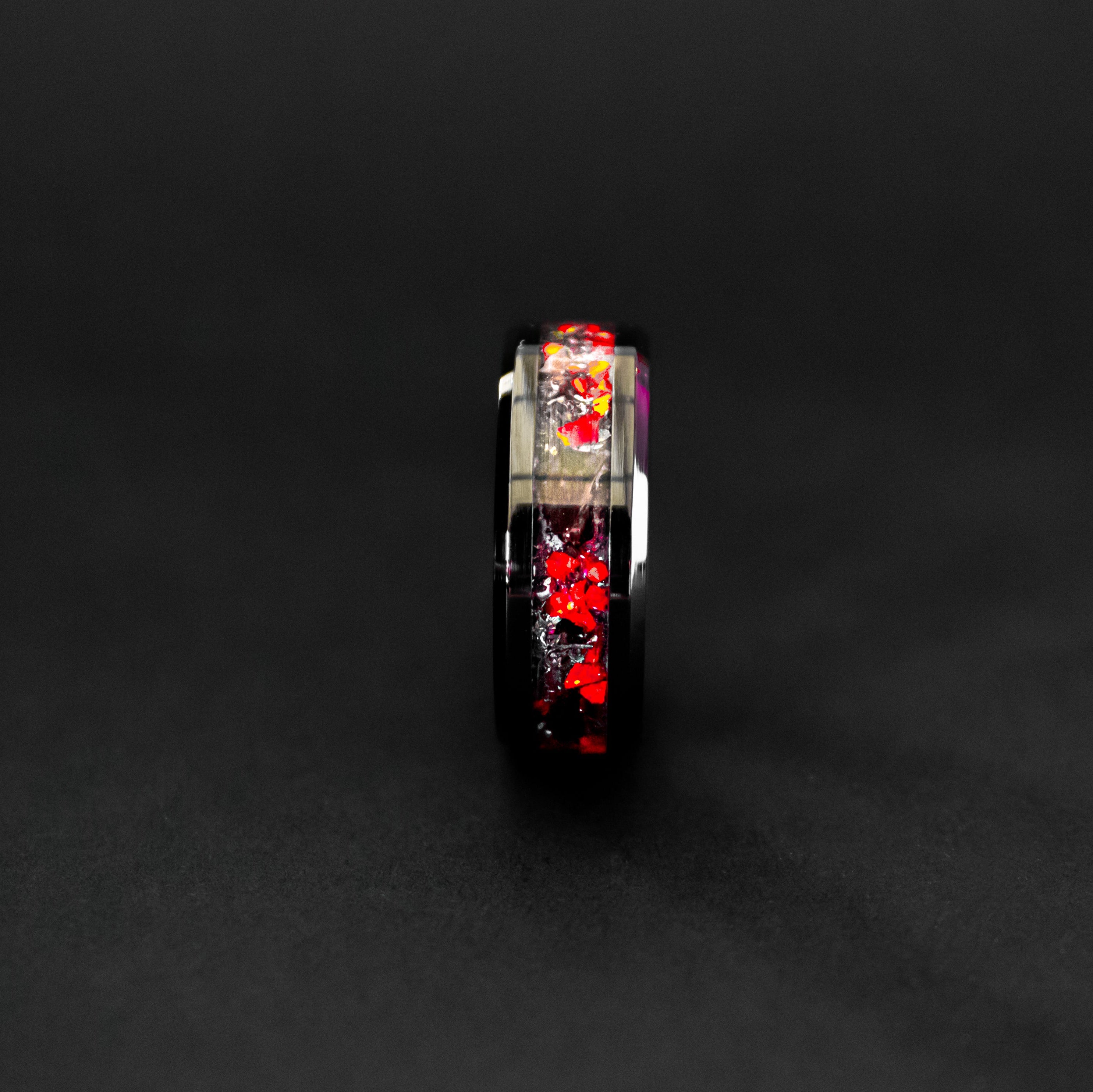 Close up of genuine T-Rex fossil and Campo del Cielo meteorite shavings suspended in red opal inlay on beveled black ceramic ring