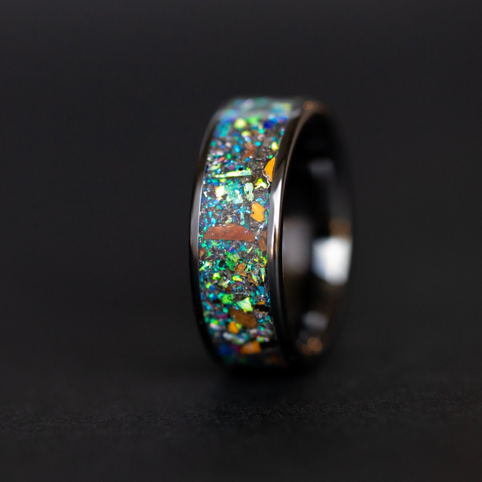 Close up of genuine T-Rex and Velociraptor bone fragments and Campo del Cielo meteorite shavings suspended in blue and green galaxy opal inlay on ceramic ring