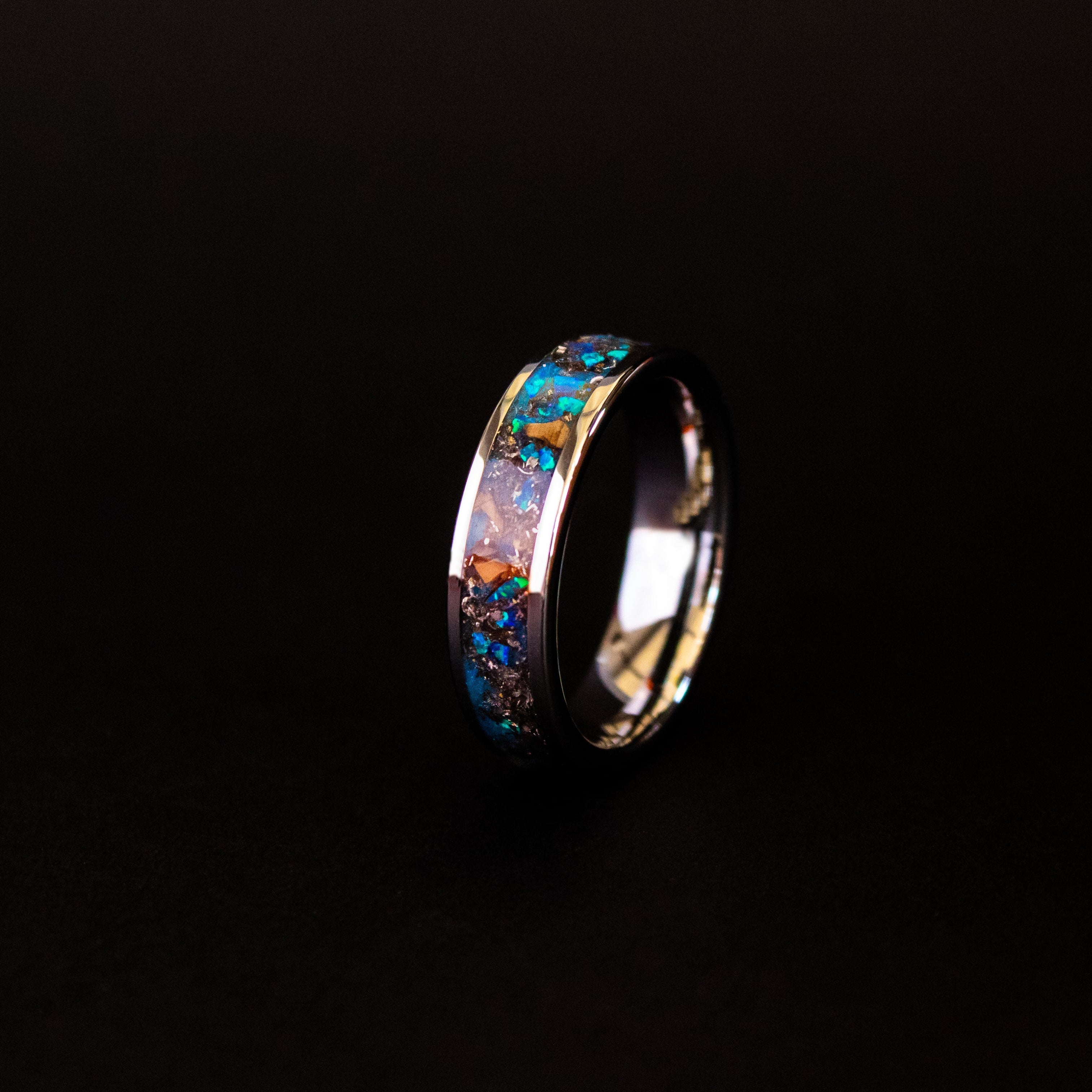 Close up of genuine Triceratops fossil and Campo del Cielo meteorite shavings suspended in blue opal inlay on beveled tungsten ring