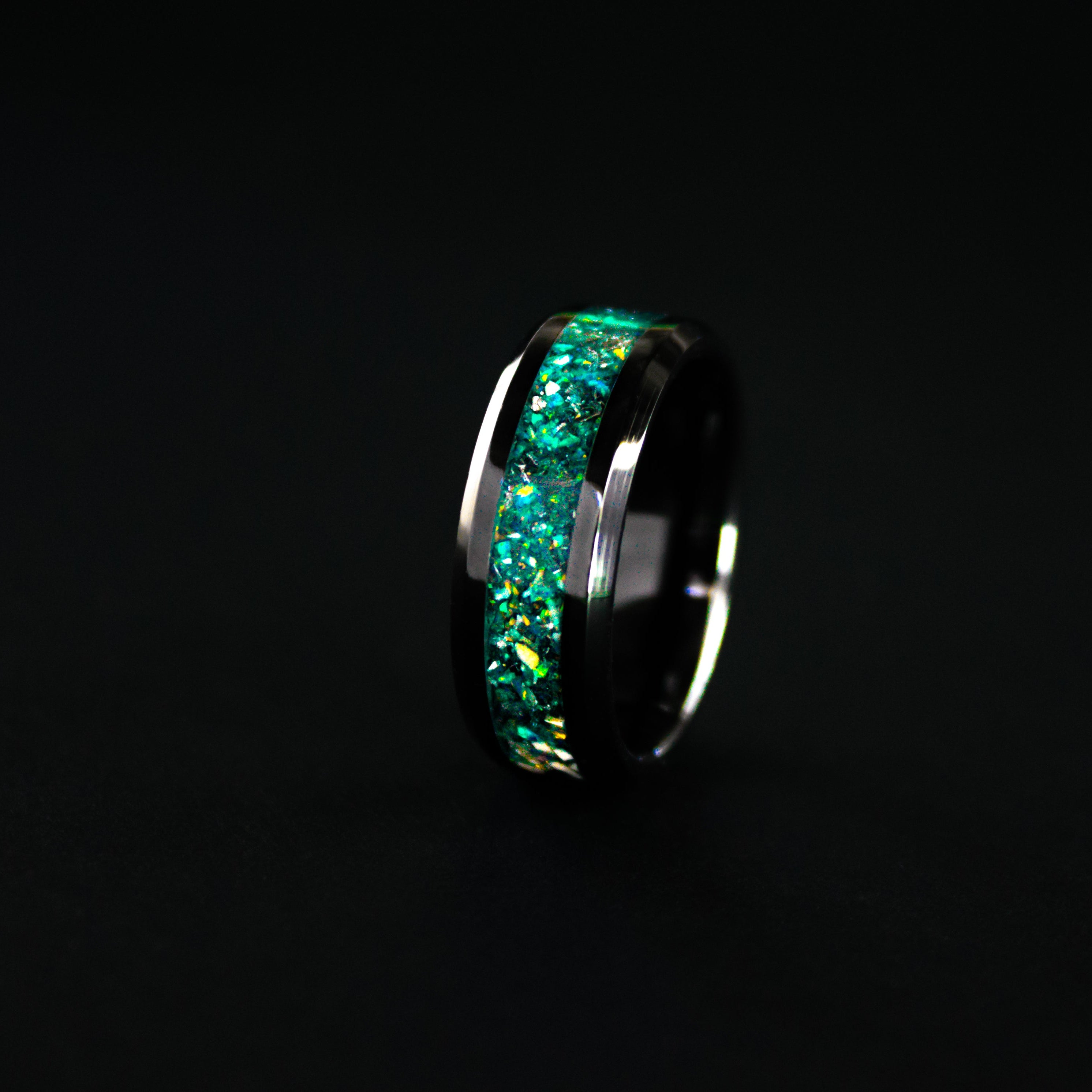 Close up of genuine Triceratops fossil and Campo del Cielo meteorite shavings suspended in teal opal inlay on beveled black ceramic ring