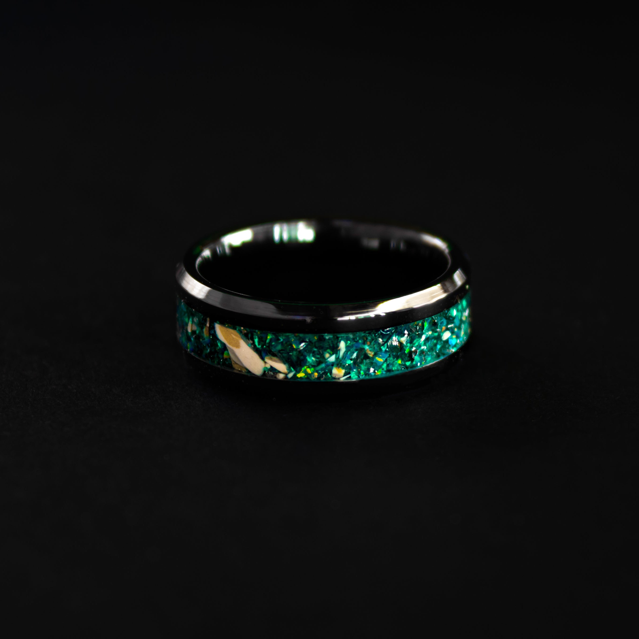 Triceratops Teal Glow ring glowing teal in total darkness showing Triceratops bone and meteorite suspended in electric teal glow in the dark inlay