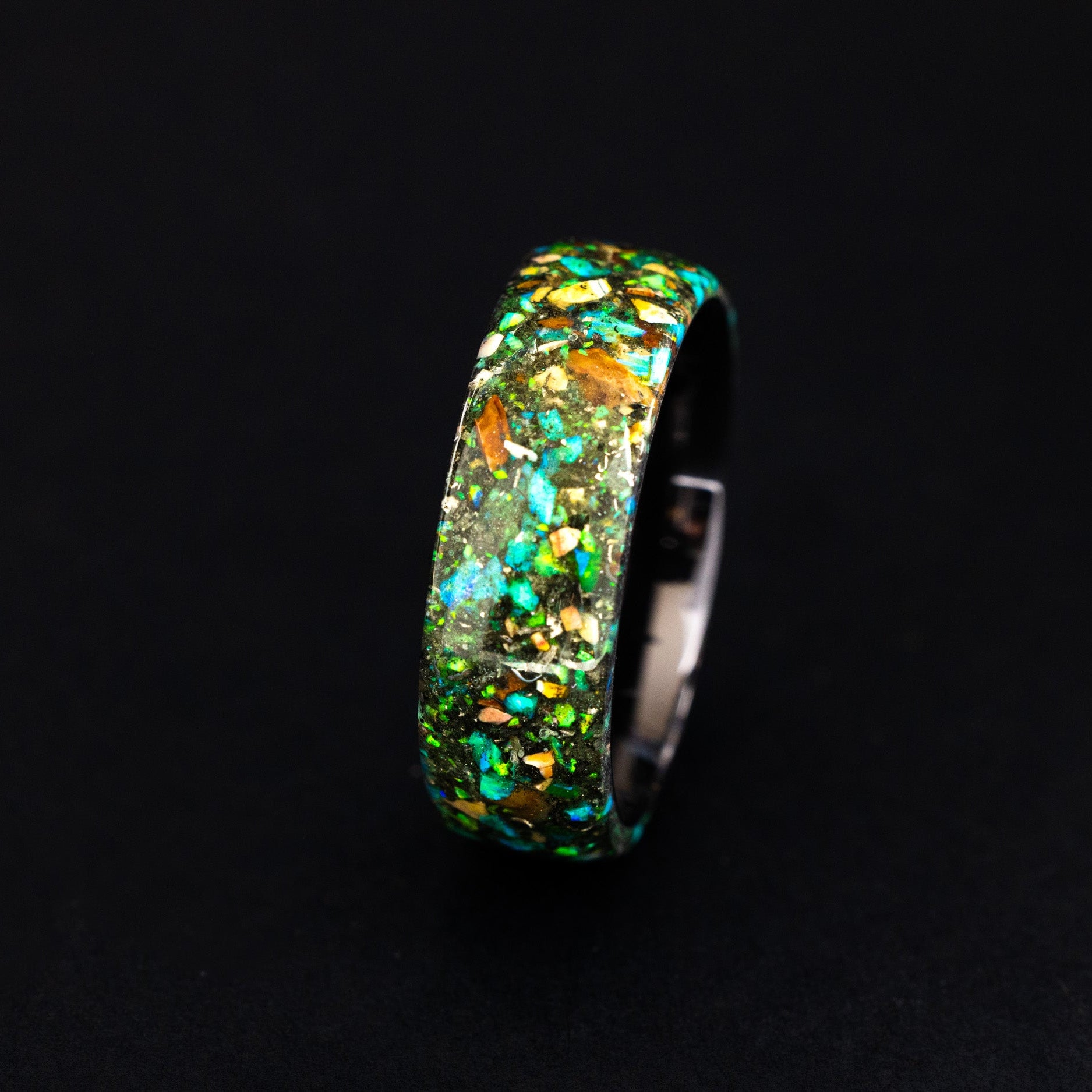 Handcrafted endless black ceramic wedding band featuring prehistoric raptor bone and vibrant green glow.