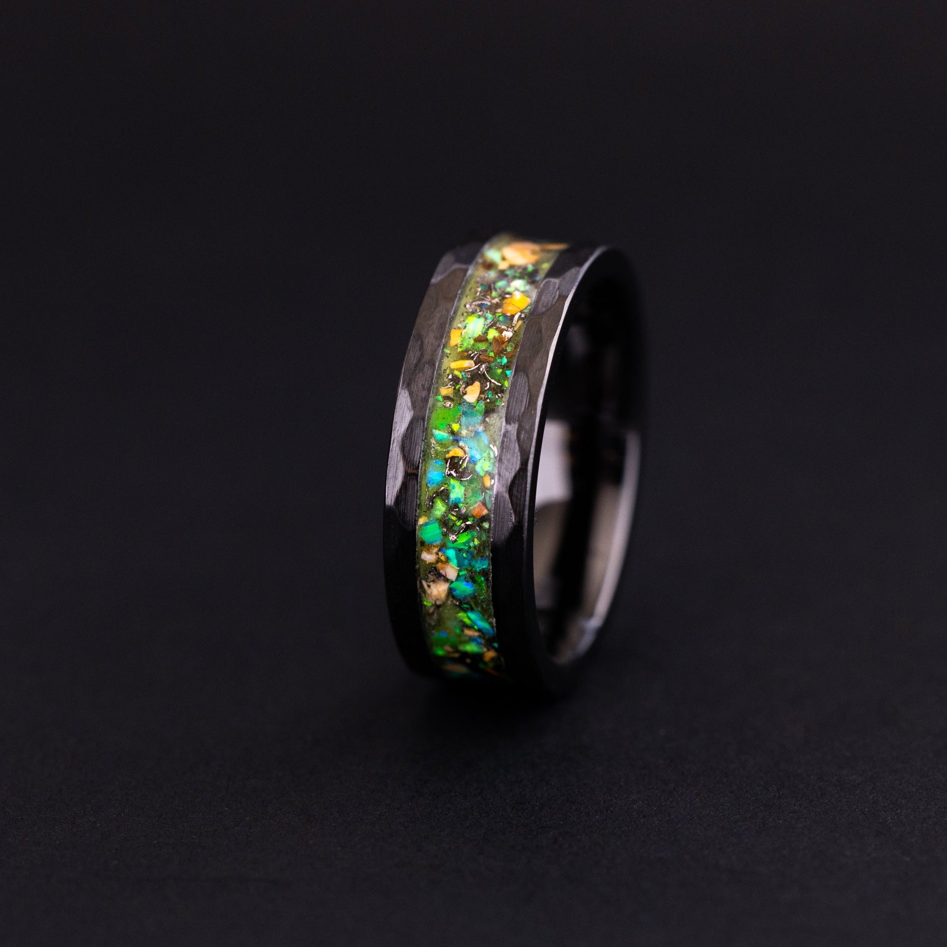 Handcrafted 8mm hammered black ceramic wedding band featuring prehistoric raptor bone and vibrant green glow.