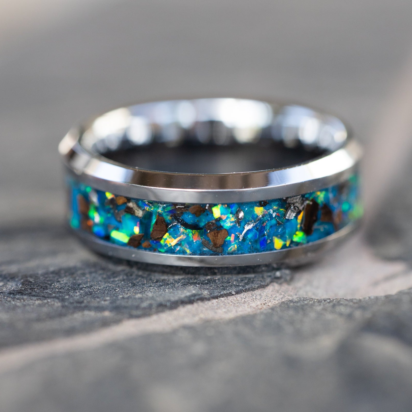 Oasis Rex Glow ring glowing blue in total darkness showing T-Rex bone and meteorite suspended in electric blue glow in the dark inlay