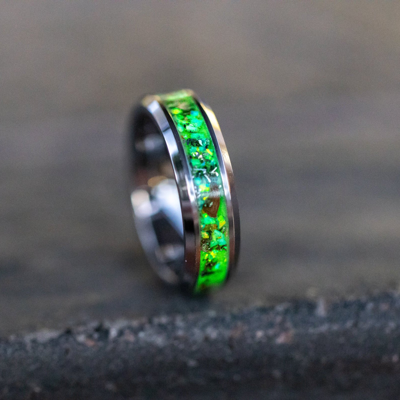 Close up of genuine Velociraptor fossil and Campo del Cielo meteorite shavings suspended in lime green opal inlay on tungsten ring