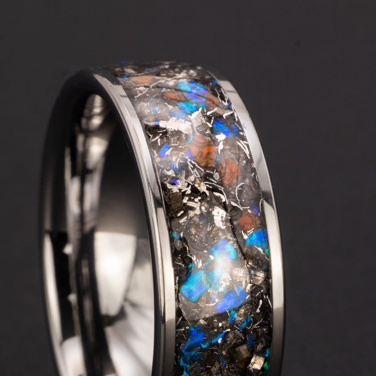 Detail shot of the Blue Gembone ring showing authentic Dinosaur Gembone fragments and meteorite shavings with flashes of blue opal catching light on wide channel tungsten band