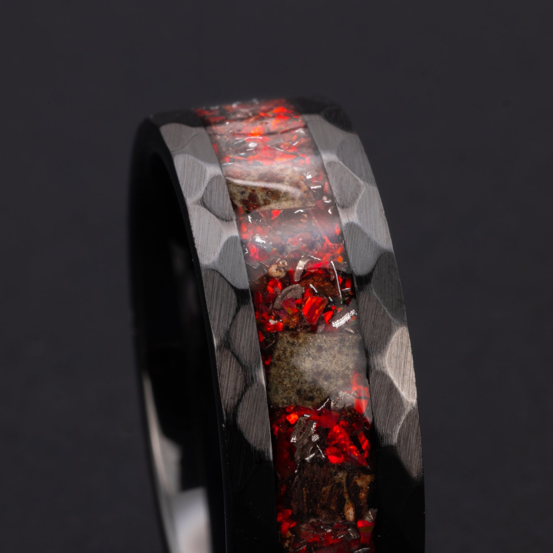 Close up of genuine T-Rex fossil and Martian meteorite shavings suspended in red opal inlay on hammered black ceramic ring