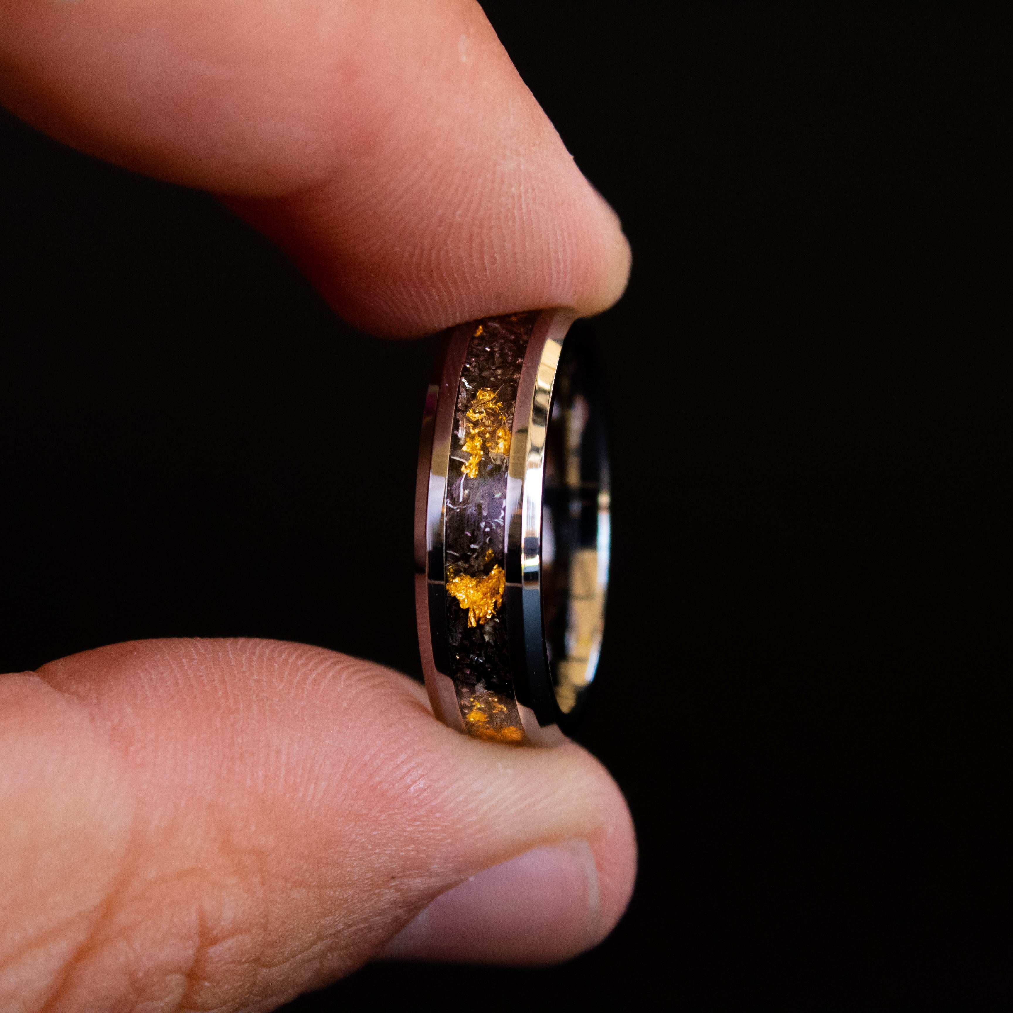Detail shot of the 24K Cosmic Gold 6mm ring showing authentic Campo del Cielo meteorite shavings and real gold metal flake catching light on beveled tungsten band