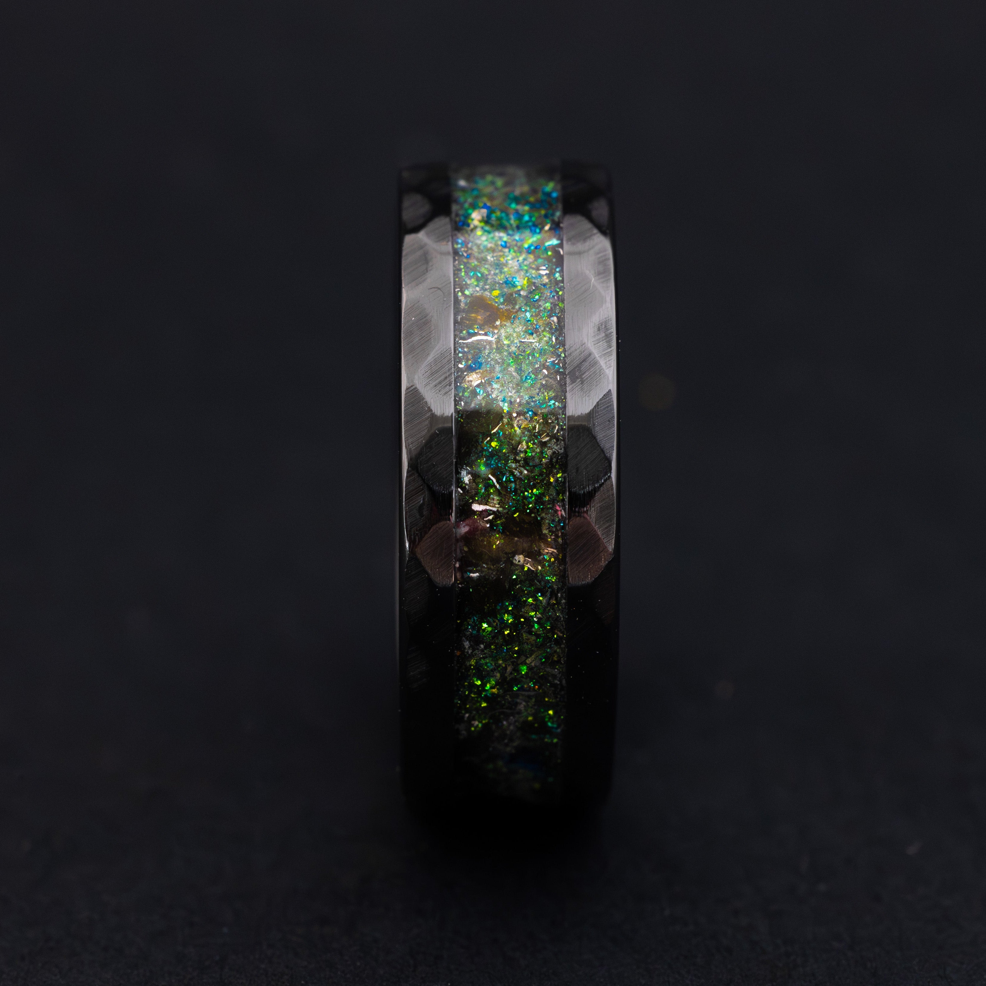 Handcrafted hammered ceramic wedding band showing the vibrant teal glow in the dark effect.