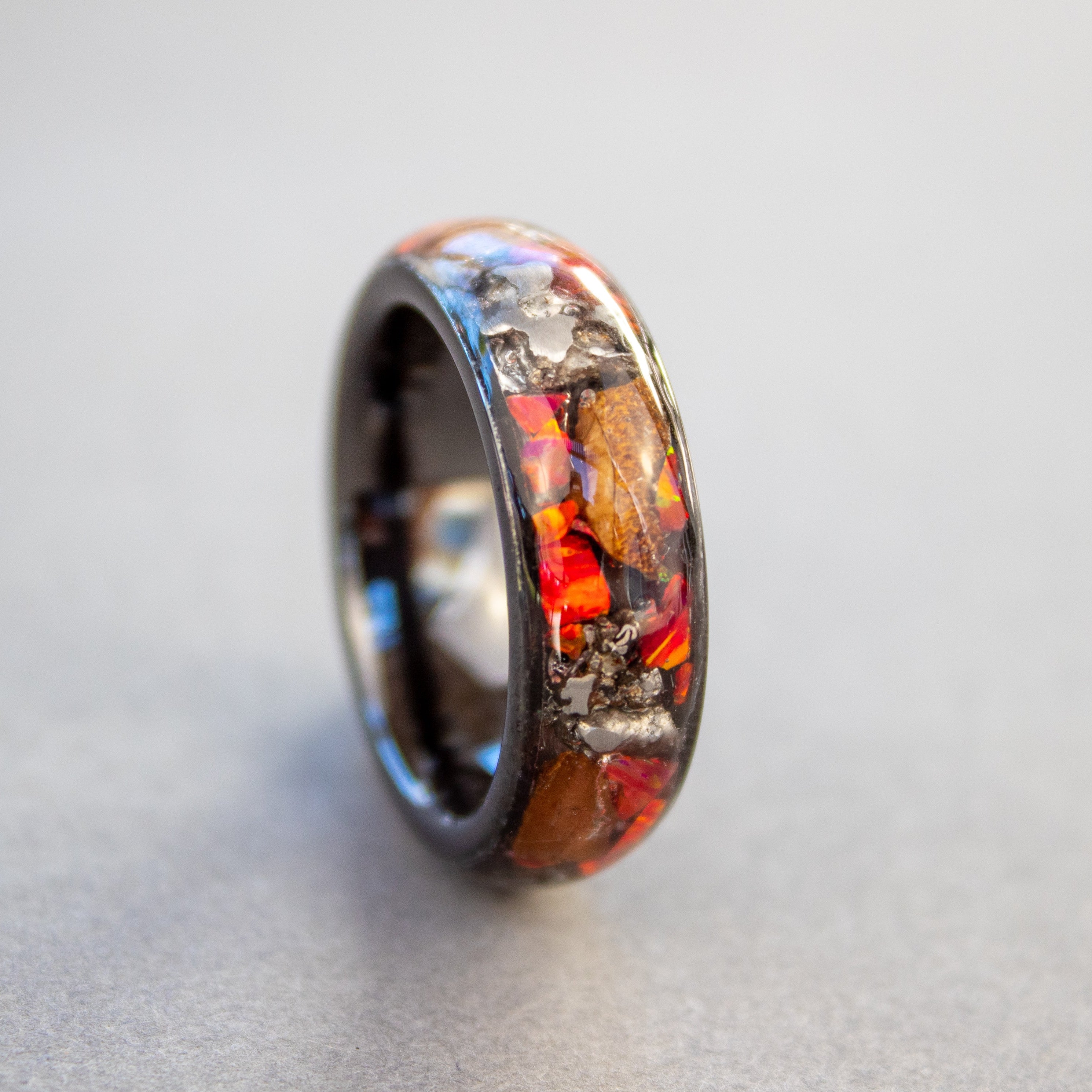 Handcrafted 8mm wide channel black ceramic mens wedding band with large authentic Triceratops bone and Campo del Cielo meteorite pieces in red opal inlay made in California