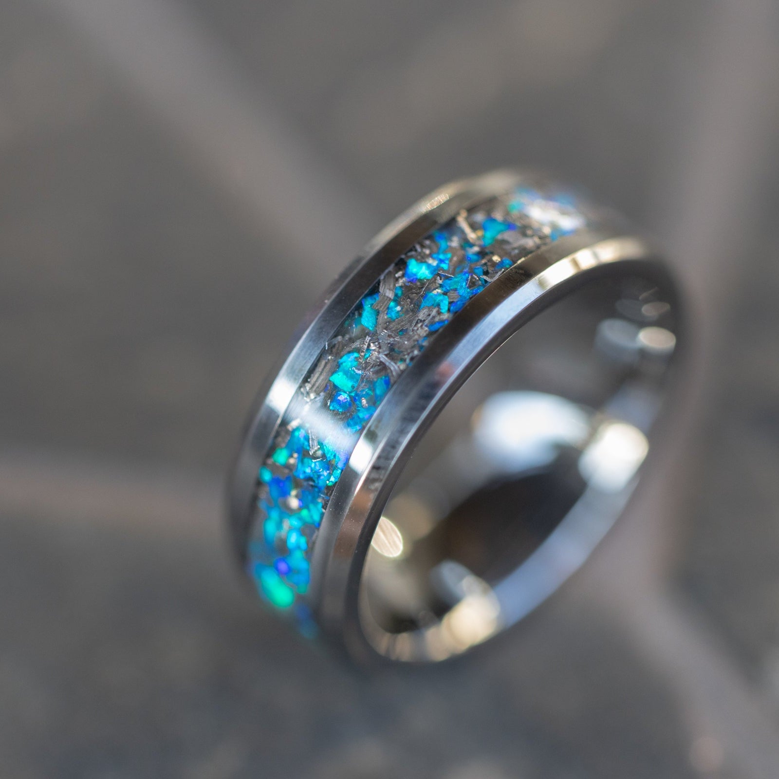 Detail shot of the Blue Orbit Tungsten ring showing authentic Campo del Cielo meteorite shavings catching light through deep blue opal inlay