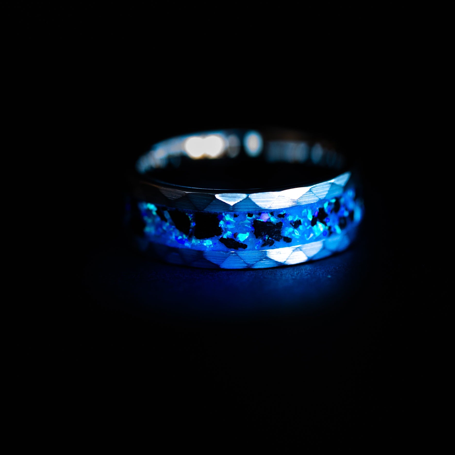 Close up of genuine Megalodon shark tooth fossil suspended in blue opal inlay on 8mm hammered tungsten ring