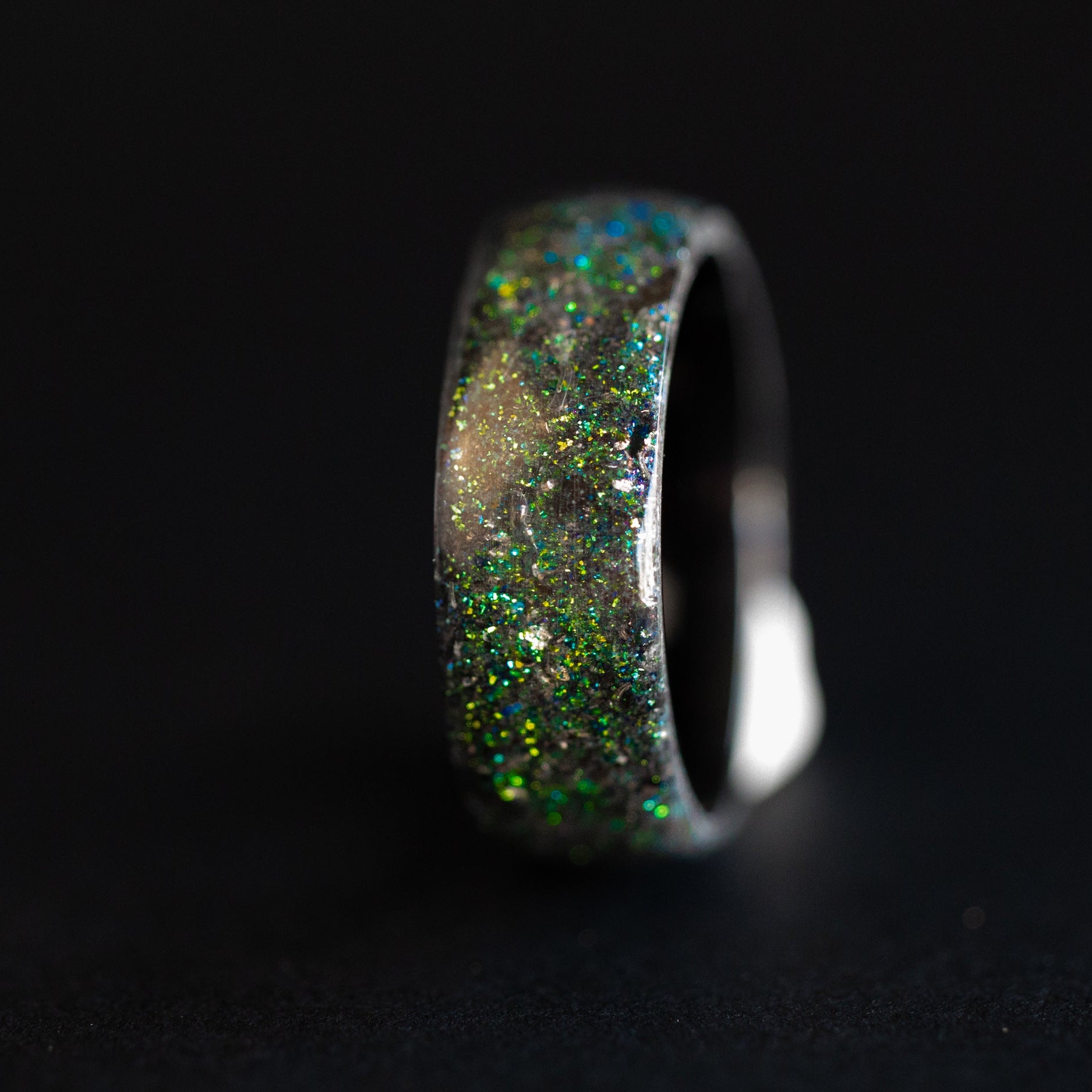 Close up of Megalodon shark tooth fossil and meteorite shavings suspended in blue and green galaxy opal inlay on endless ceramic ring