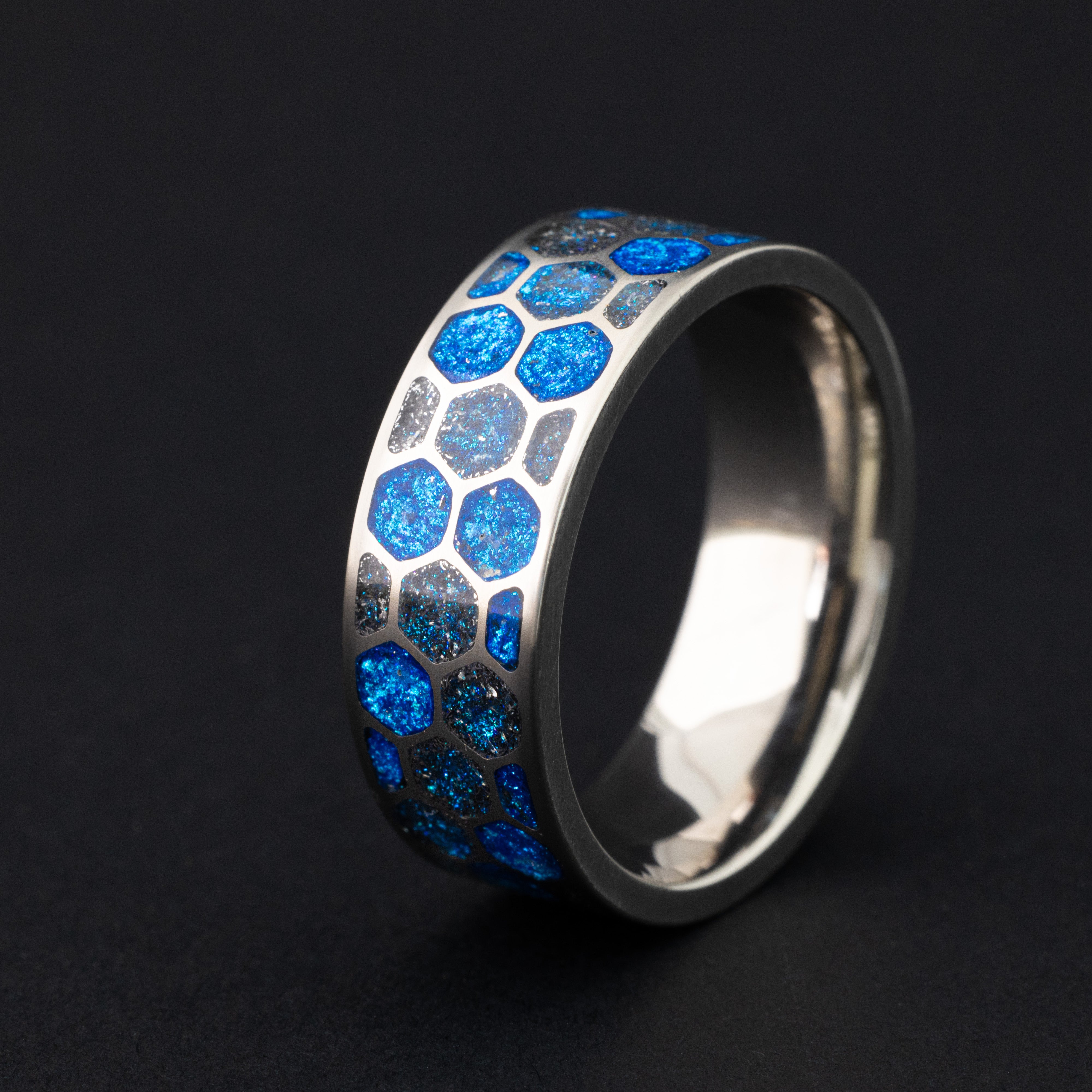 8mm titanium honeycomb ring with authentic Campo del Cielo meteorite pieces in blue resin filled hexagonal cells glowing blue in the dark