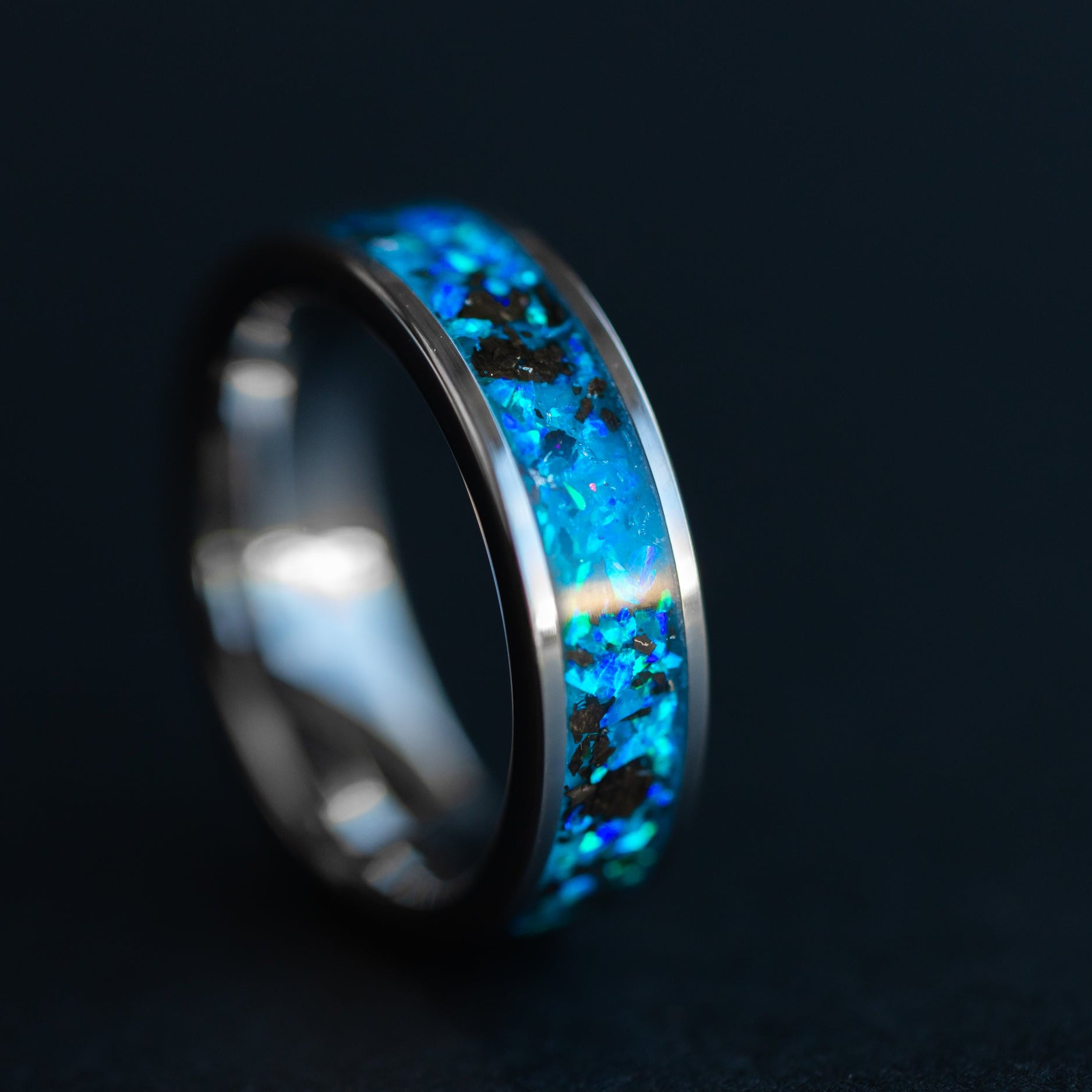 Blue Megalodon Abyss ring glowing blue in the dark after UV light charge showing Megalodon tooth fossil suspended in luminous blue opal inlay