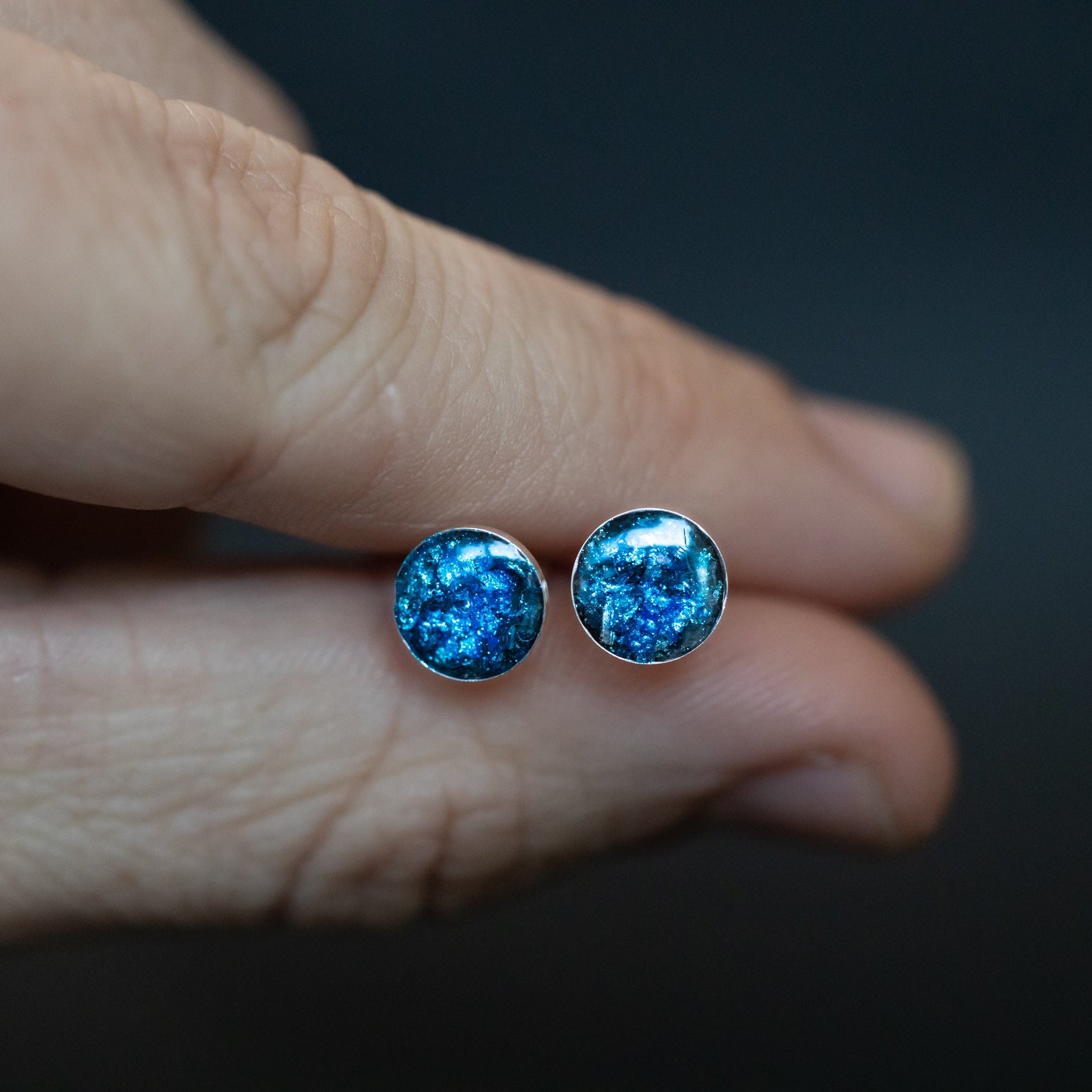 Close-up of the Blue Nova Studs blue stud earrings showing Campo Del Cielo iron meteorite set in deep blue glitter evoking a starry night