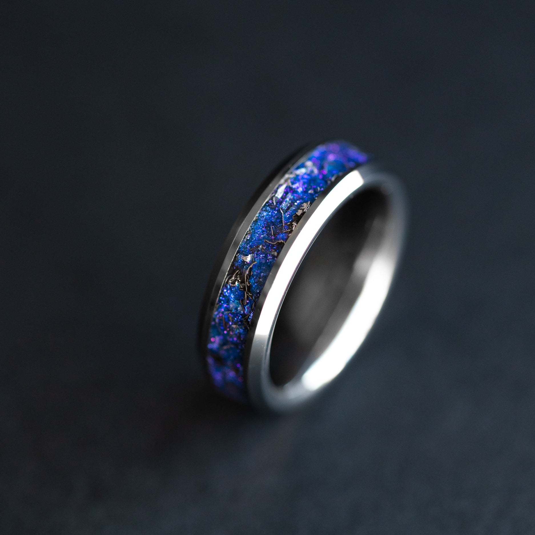 Close up of genuine Campo del Cielo meteorite shavings suspended in blue and purple galaxy pigment inlay on 6mm beveled tungsten ring