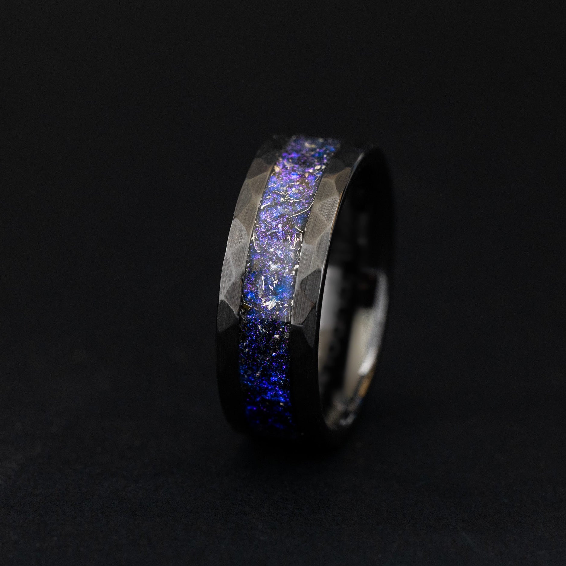 Close up of meteorite shavings in a shifting blue and purple hammered ceramic ring.