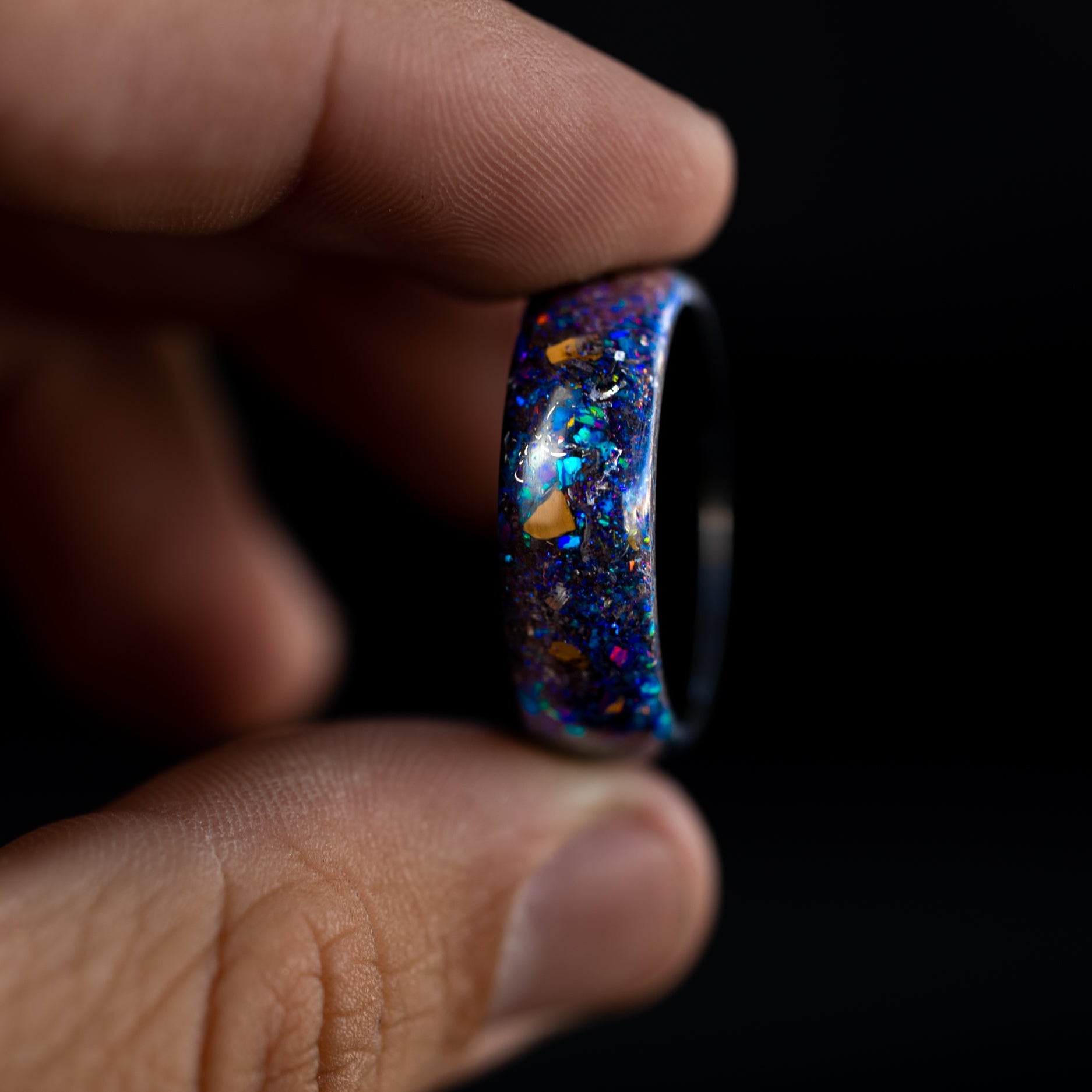 Close up of dinosaur bone and purple galaxy glitter in a seamless black ceramic ring.