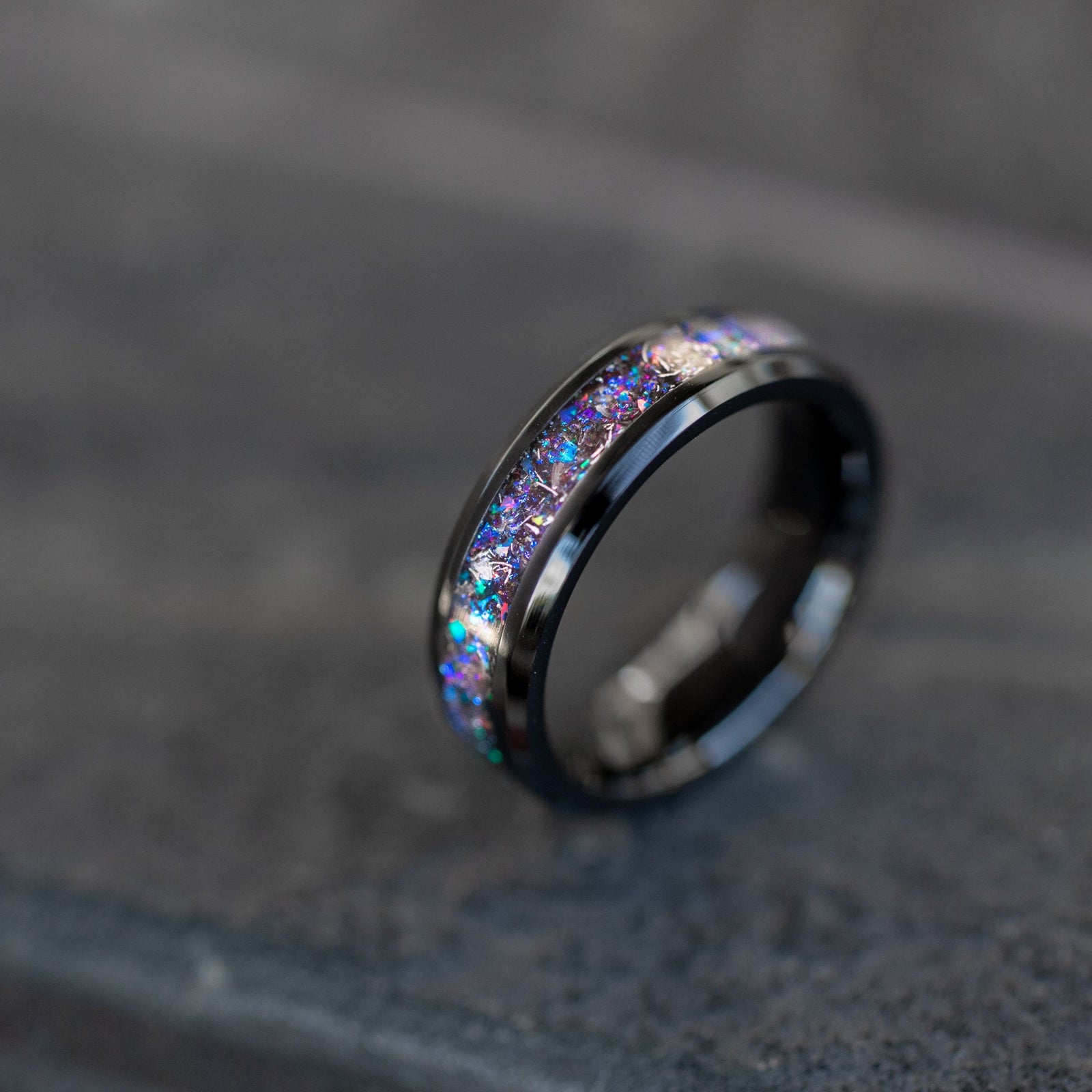 Close up of genuine Campo del Cielo meteorite shavings suspended in blue and purple opal galaxy pigment inlay on beveled ceramic ring
