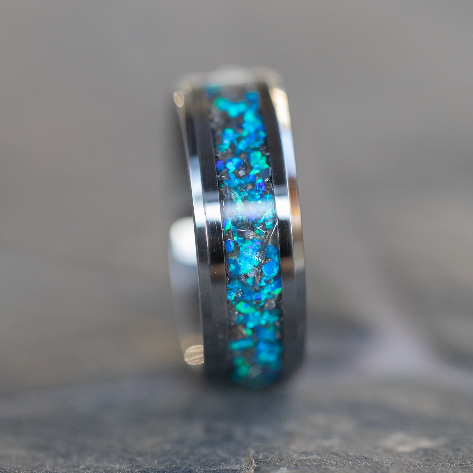Close up of genuine Campo del Cielo meteorite shavings suspended in premium blue opal inlay on 8mm beveled tungsten ring