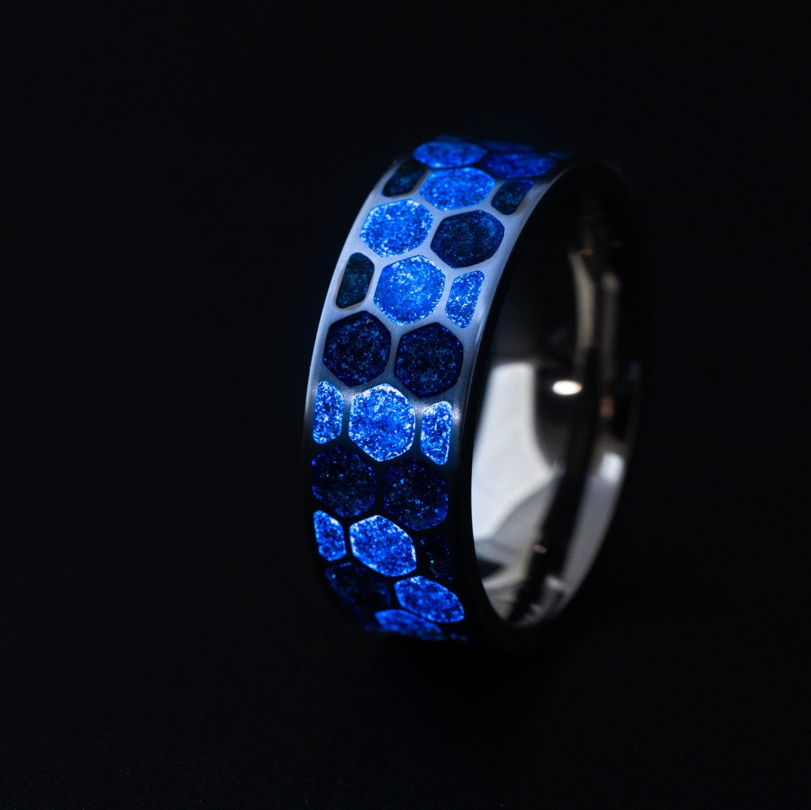 Close up of genuine Campo del Cielo meteorite pieces suspended in blue resin within individual honeycomb cells on titanium ring
