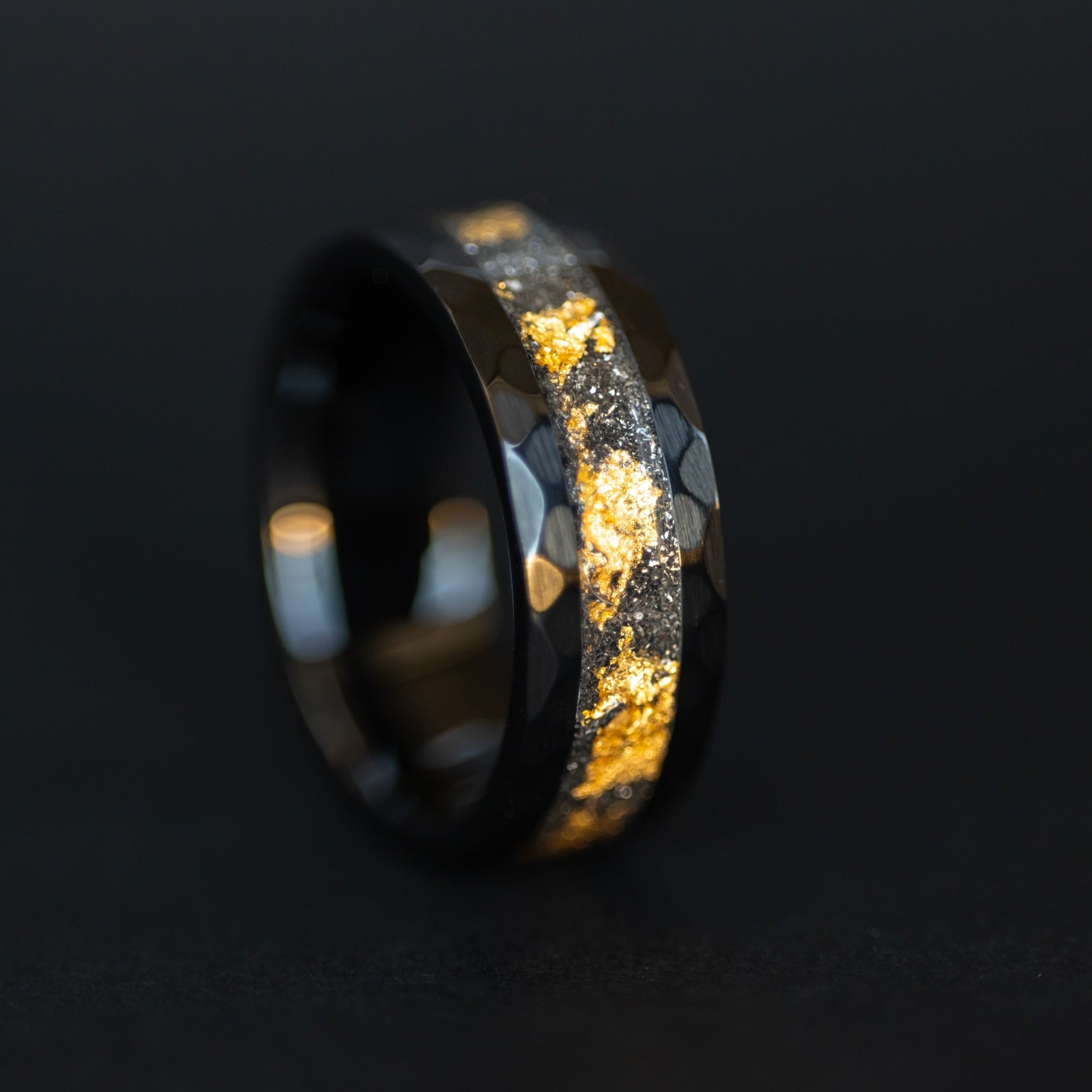Close up of genuine Campo del Cielo meteorite shavings layered with real gold leaf inlay on hammered black ceramic ring
