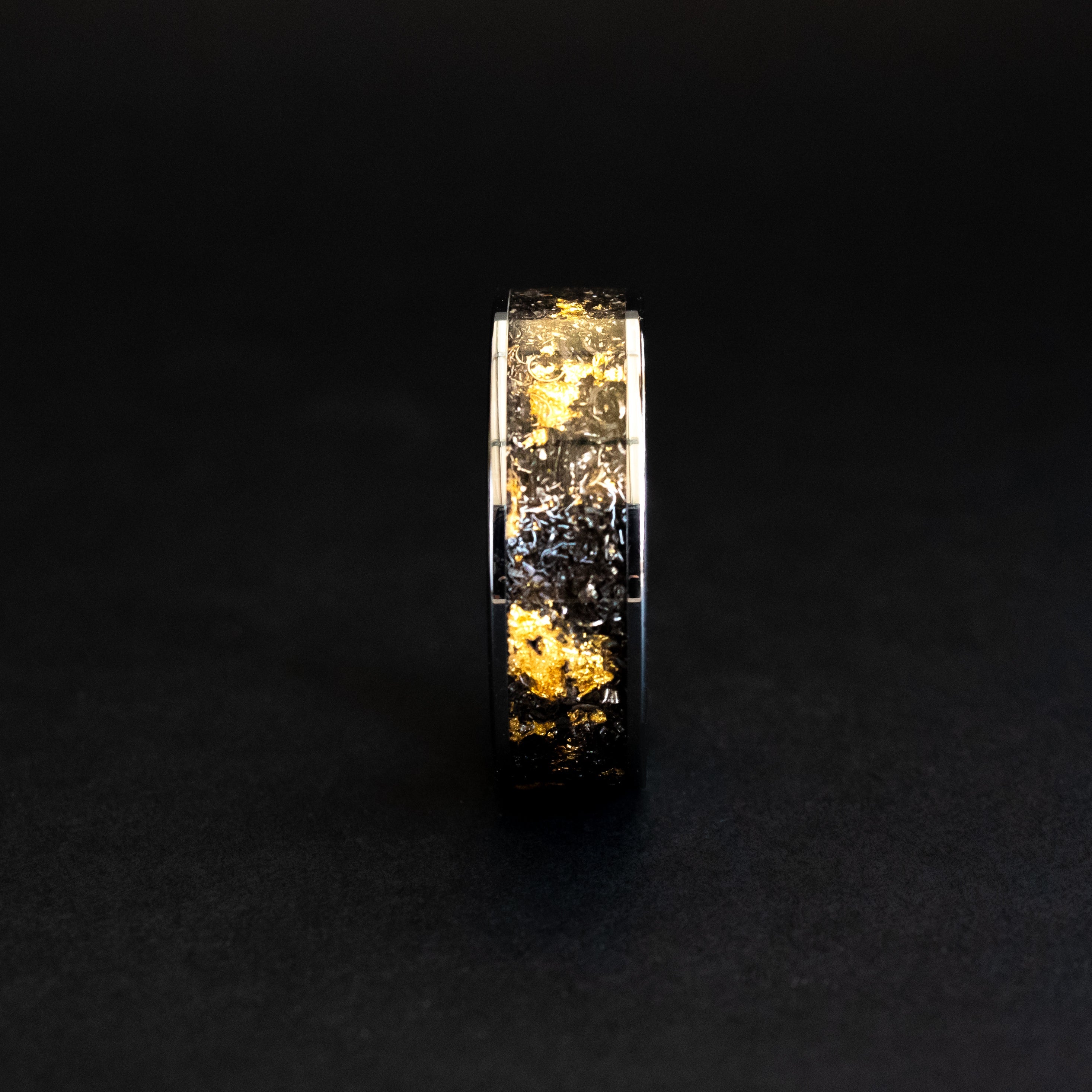 Close up of genuine Campo del Cielo meteorite shavings mixed with real gold metal flake inlay on wide channel tungsten ring