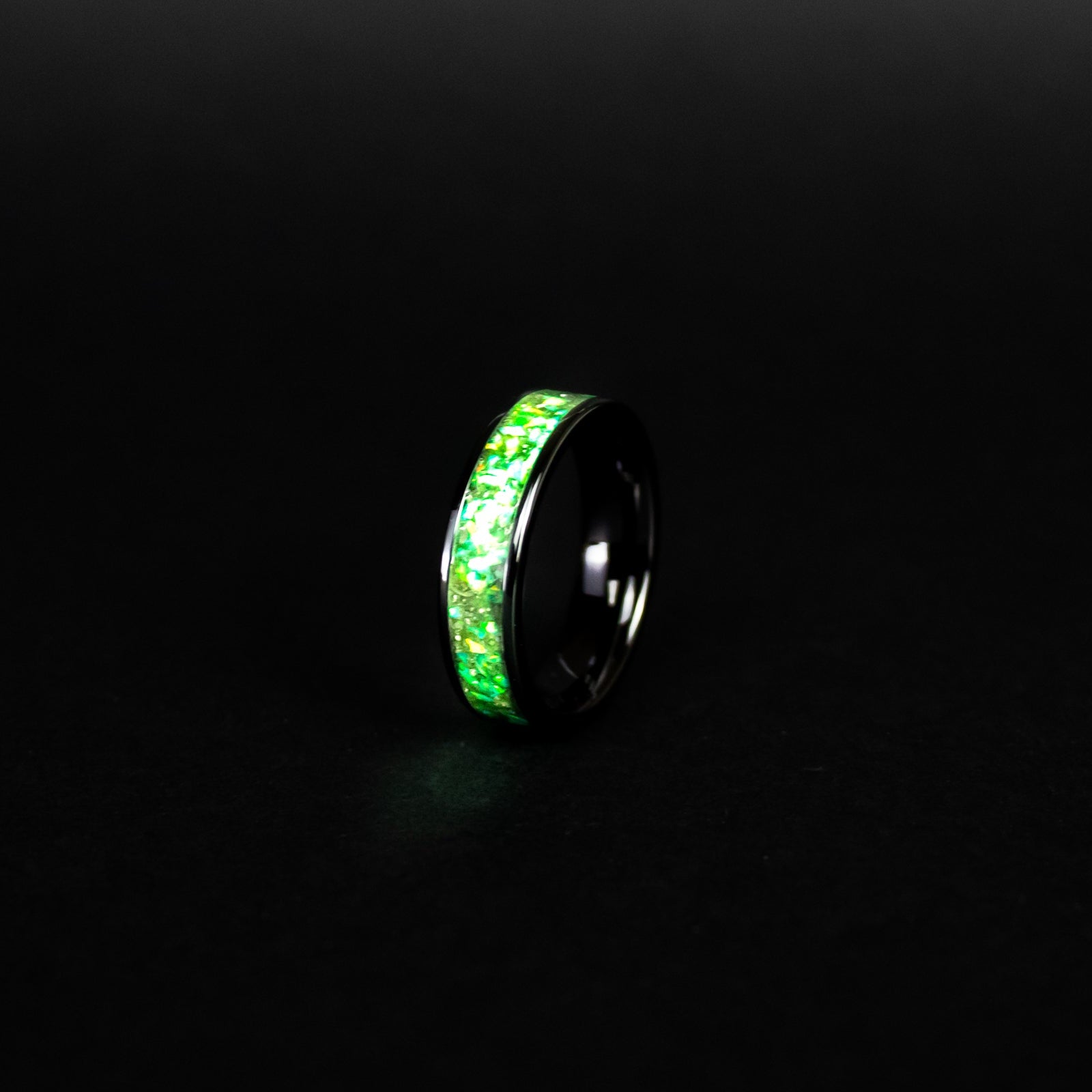 Close up of genuine Campo del Cielo meteorite shavings suspended in green opal inlay on wide channel black ceramic ring