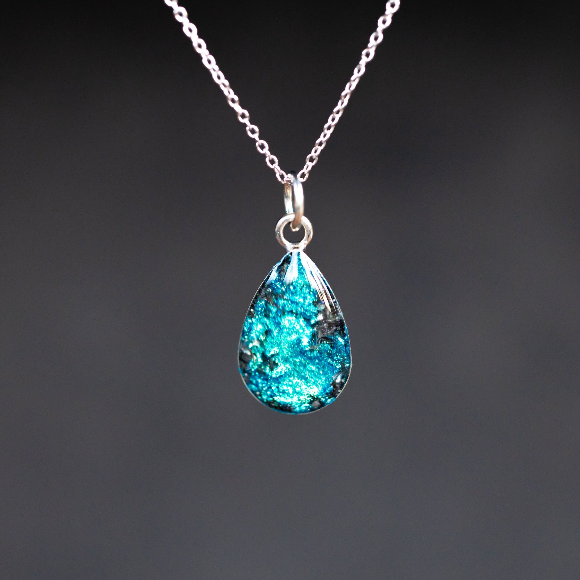 Close-up of the Cobalt Heart blue heart necklace showing Campo Del Cielo iron meteorite fragments set in deep blue glitter resin evoking a starry night