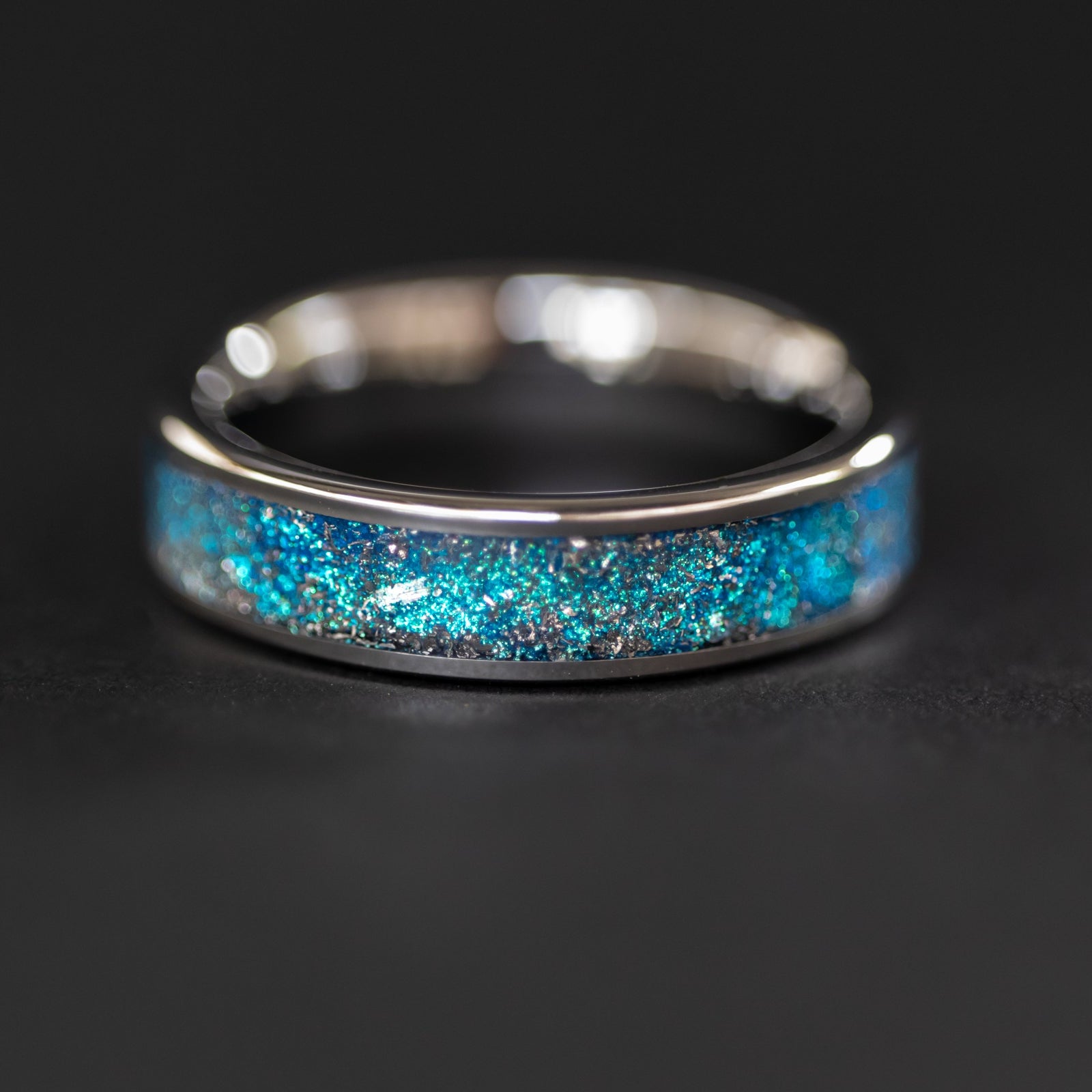 Detail shot of the Cobalt Orbit Slim ring showing authentic Campo del Cielo meteorite shavings catching light through deep blue glitter pigment inlay on tungsten band
