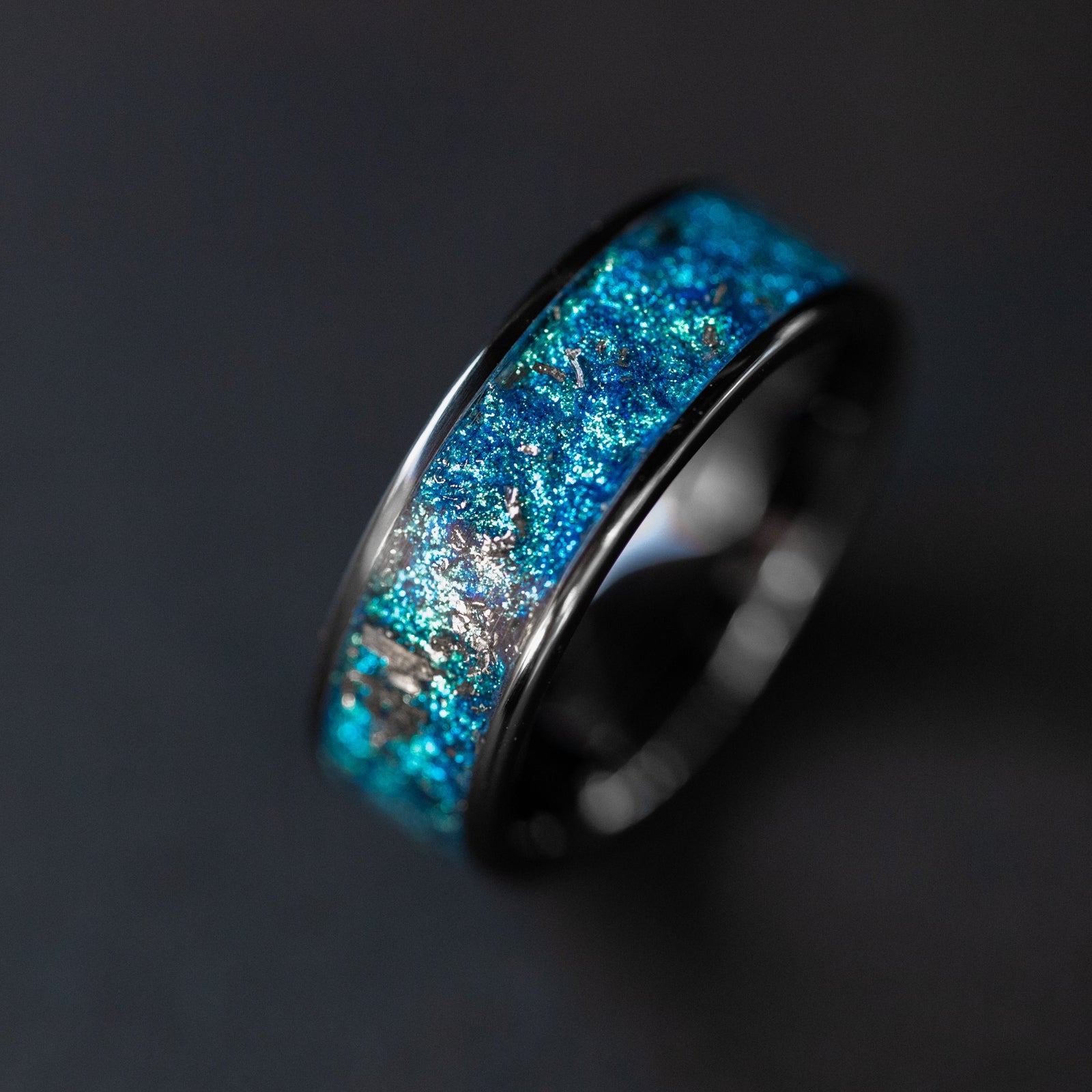 Detail shot of the Cobalt Orbit Wide ring showing authentic Campo del Cielo meteorite shavings catching light through deep blue glitter pigment inlay on wide channel ceramic band