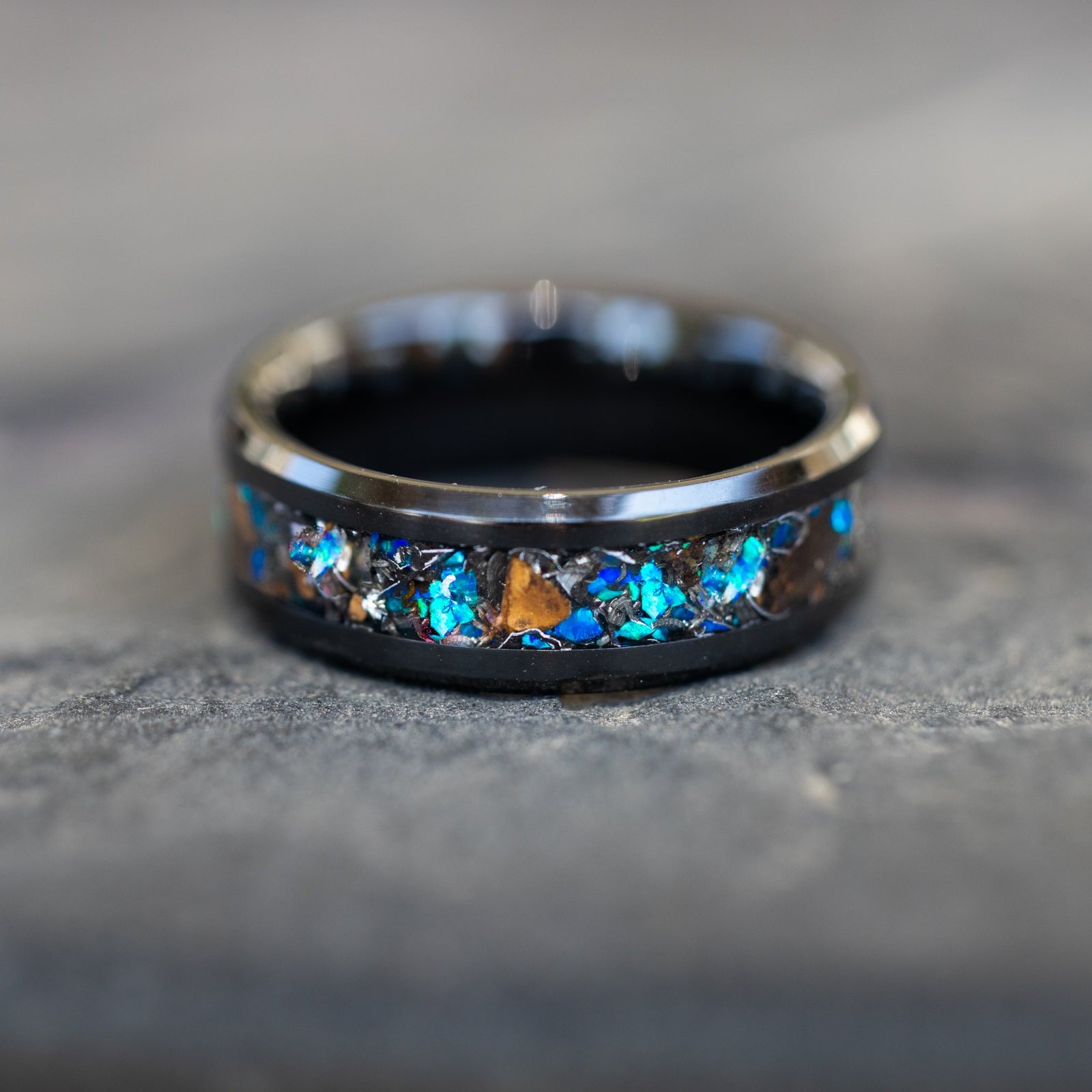 Detail shot of the Cobalt Raptor Ceramic ring showing authentic Velociraptor bone fragments and meteorite shavings catching light through blue opal inlay