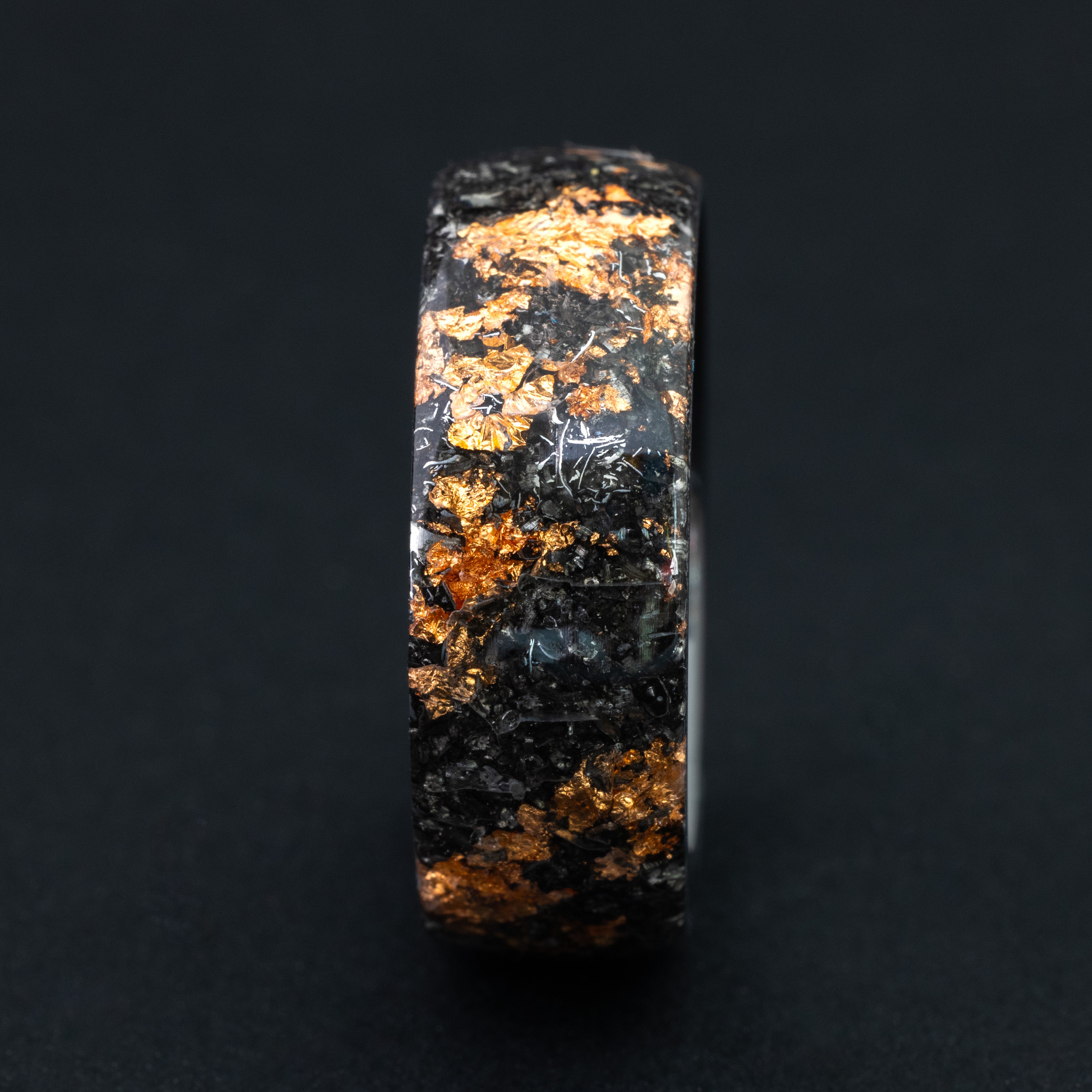 Close up of copper shards and meteorite shavings in a 360-degree wrap black ceramic ring.