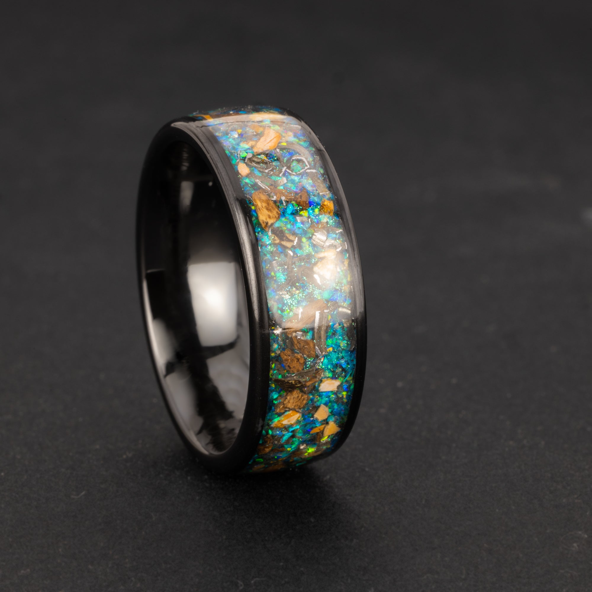 Handcrafted dinosaur fossil and meteorite 8mm wide channel black ceramic mens wedding band with real T-Rex bone, real velociraptor bone, and galaxy opal inlay