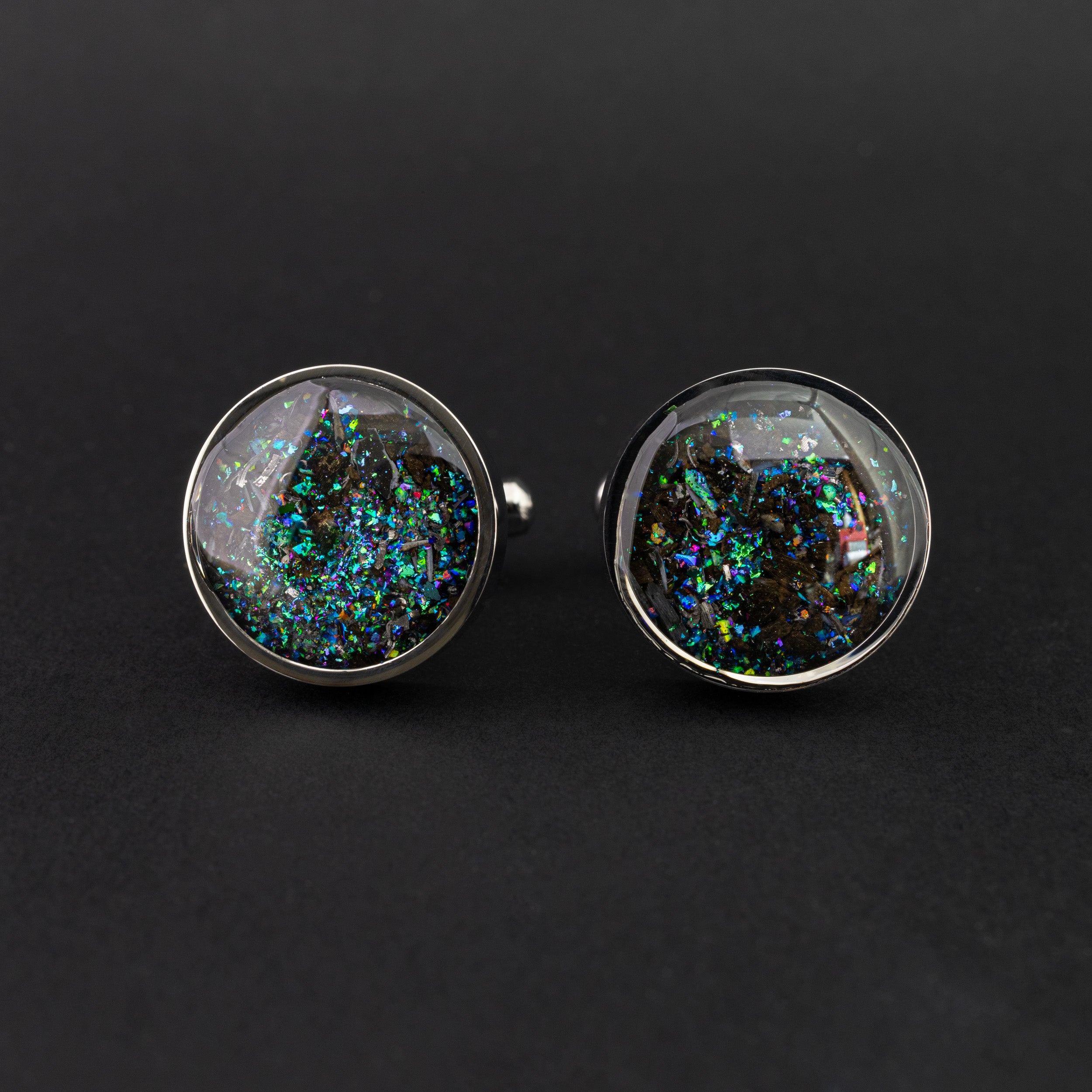 Close-up of the Deep Sea Megalodon Cufflinks showing real megalodon shark tooth, Campo Del Cielo meteorite, and a shifting blend of blue, green, and multicolored glitter in polished silver-tone stainless steel