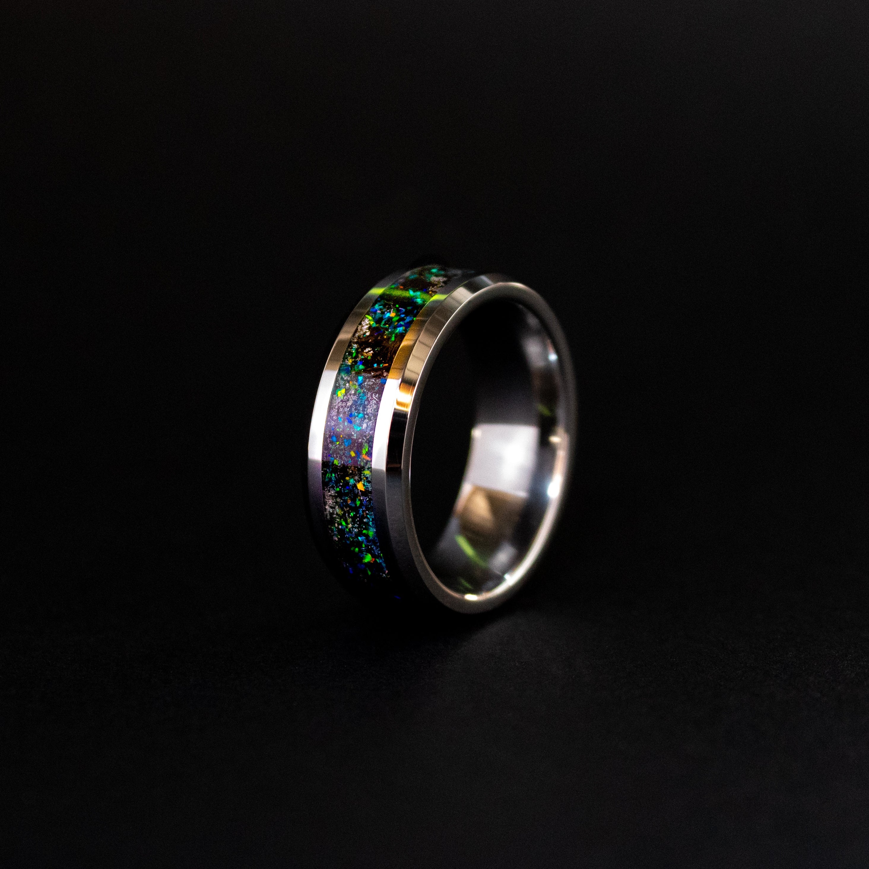 Detail shot of the Deep Sea Megalodon ring showing authentic Megalodon tooth fragments and meteorite shavings catching light through blue and green opal iridescent inlay
