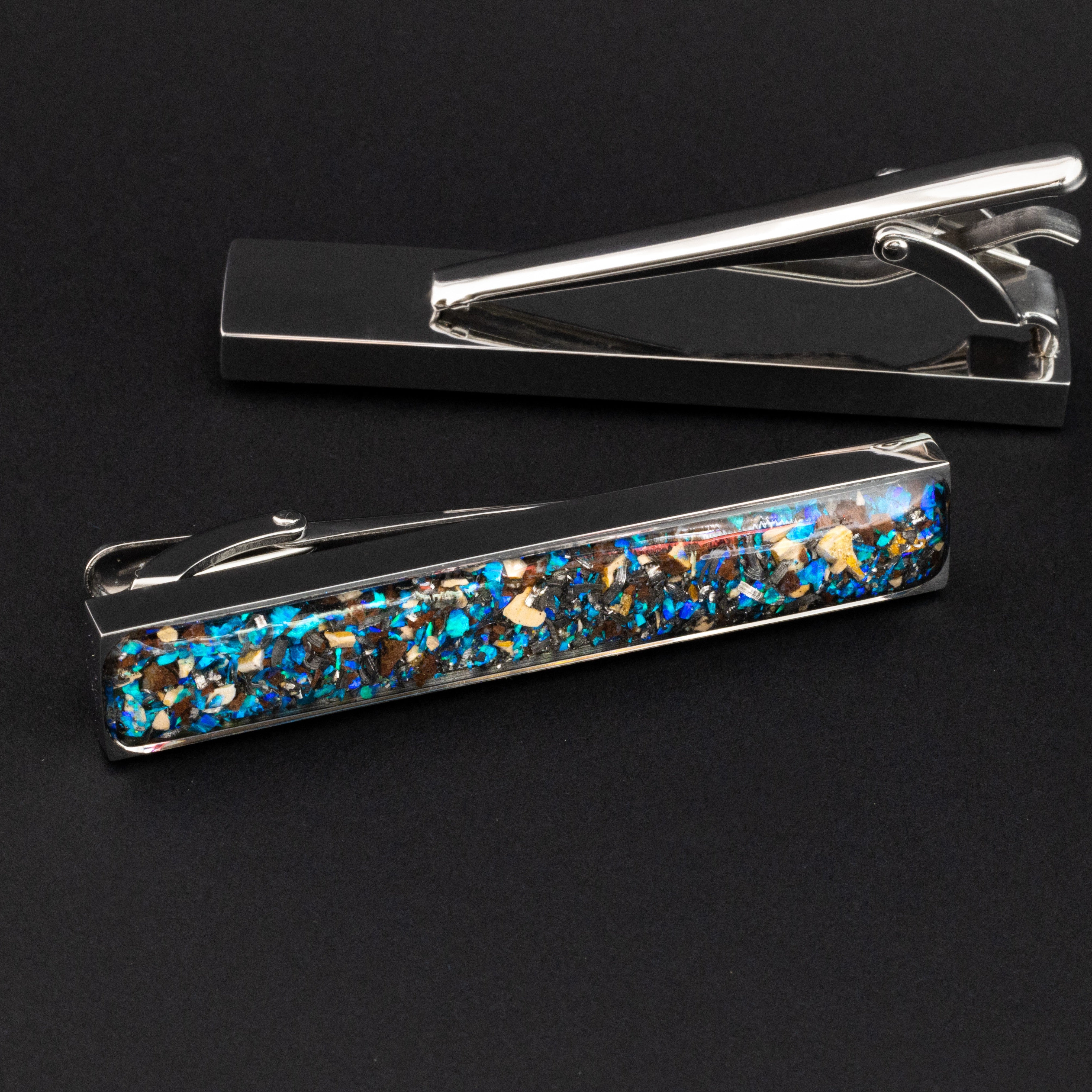 Close-up of the Dinosaur Bone Tie Clip showing Campo Del Cielo iron meteorite, real dinosaur bone, agatized dinosaur gembone, and blue opal set in polished silver-tone stainless steel