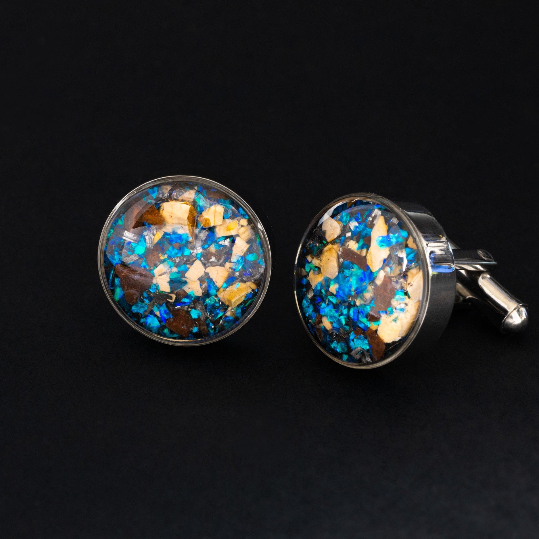 Close-up of the Dinosaur Meteorite Cufflinks showing Campo Del Cielo iron meteorite, real dinosaur bone, agatized dinosaur gembone, and blue opal set in polished silver-tone stainless steel