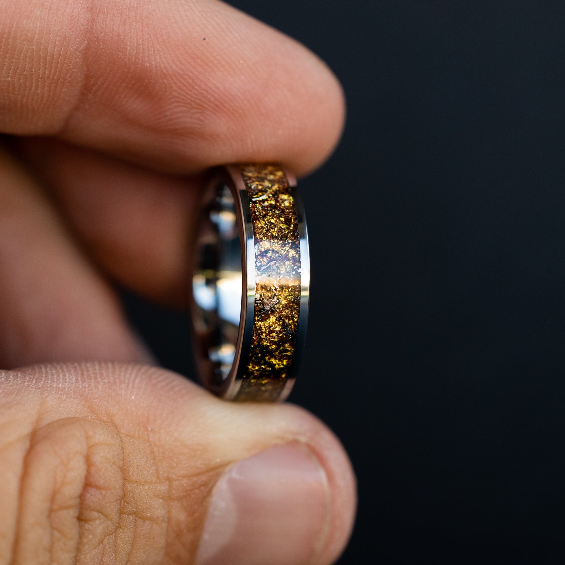 Detail shot of the Gilded Cosmos ring showing authentic Campo del Cielo meteorite shavings catching light through warm gold galaxy pigment inlay