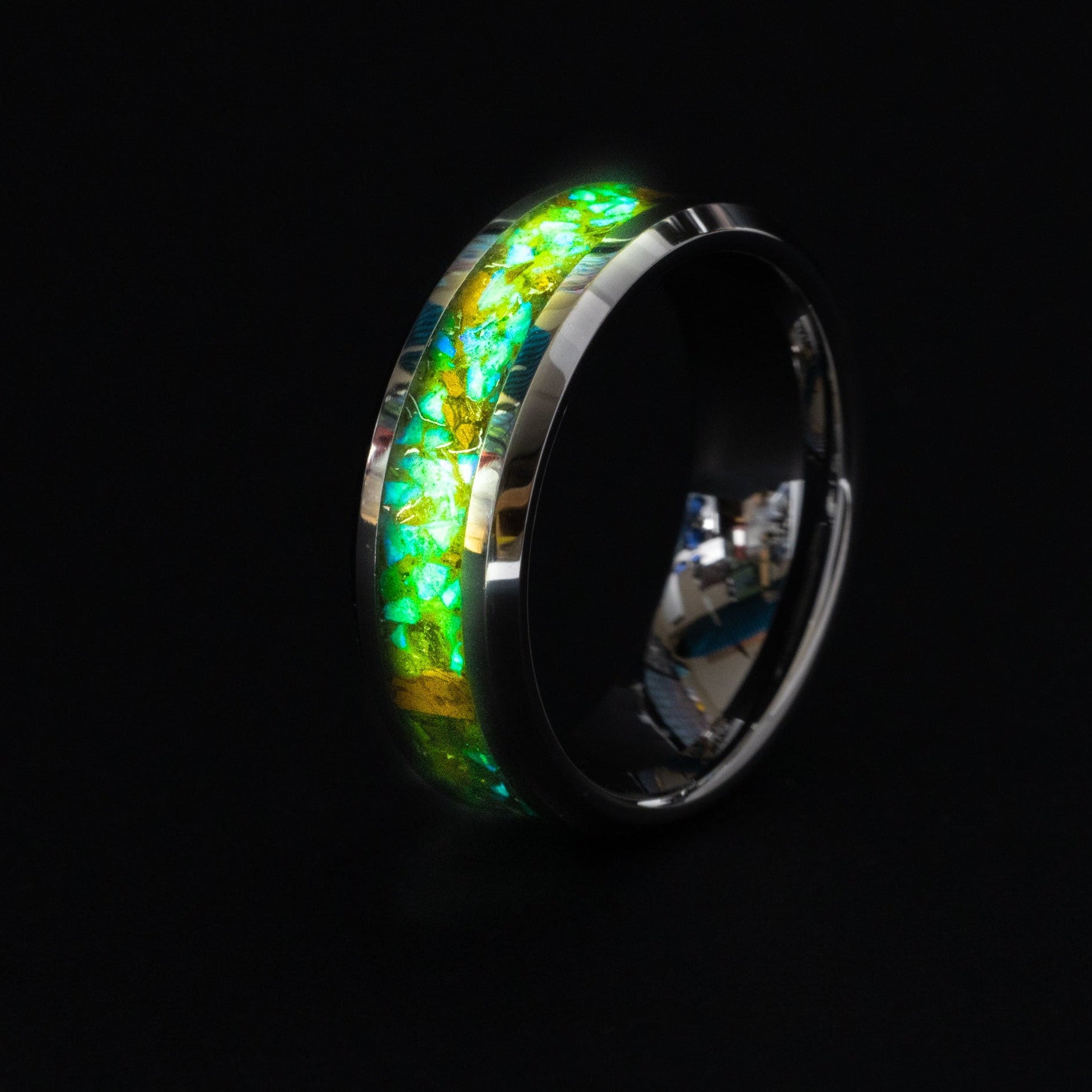 Close up of dinosaur bone and green opals in a glowing 8mm beveled tungsten ring.