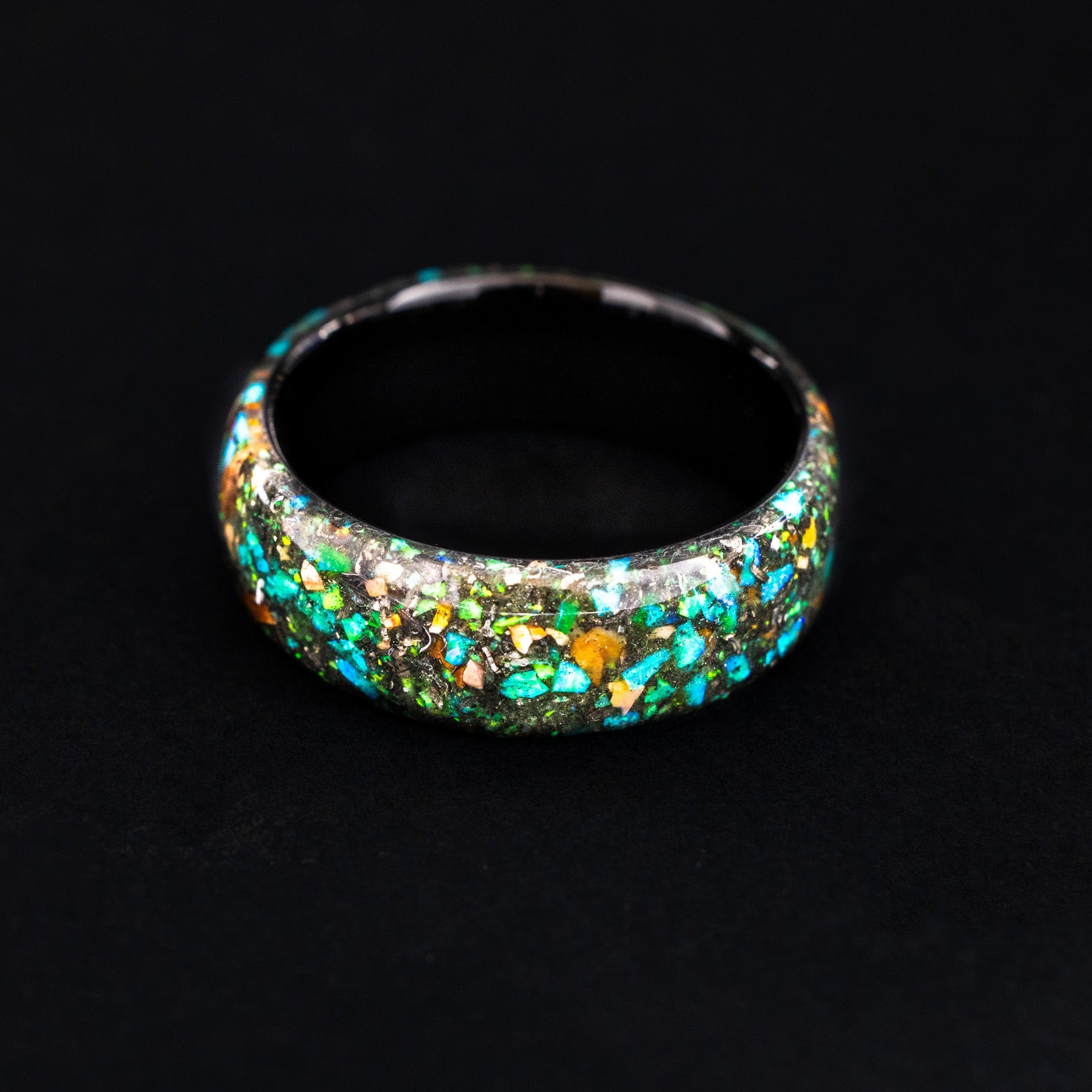 endless black ceramic wedding band featuring prehistoric raptor bone and vibrant green glow.