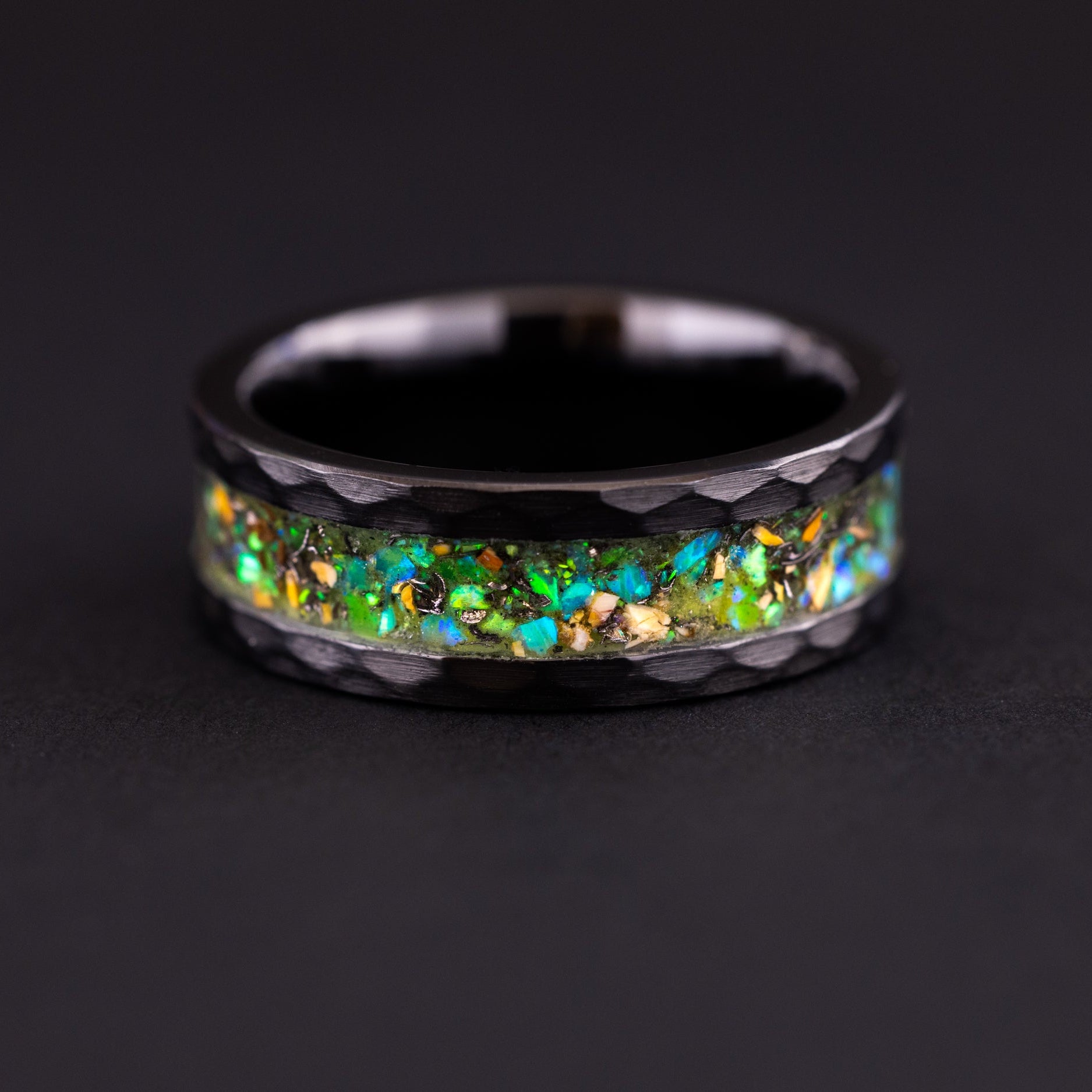 8mm hammered black ceramic wedding band featuring prehistoric raptor bone and vibrant green glow.