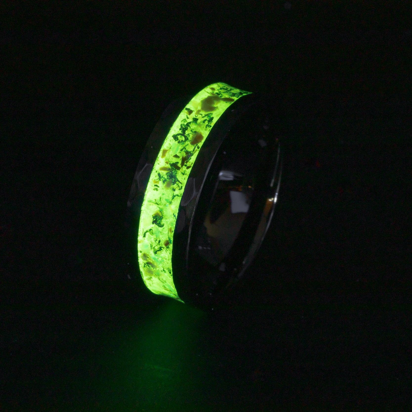 Close up of dinosaur bone and lime green opals in a glowing 8mm hammered ceramic ring