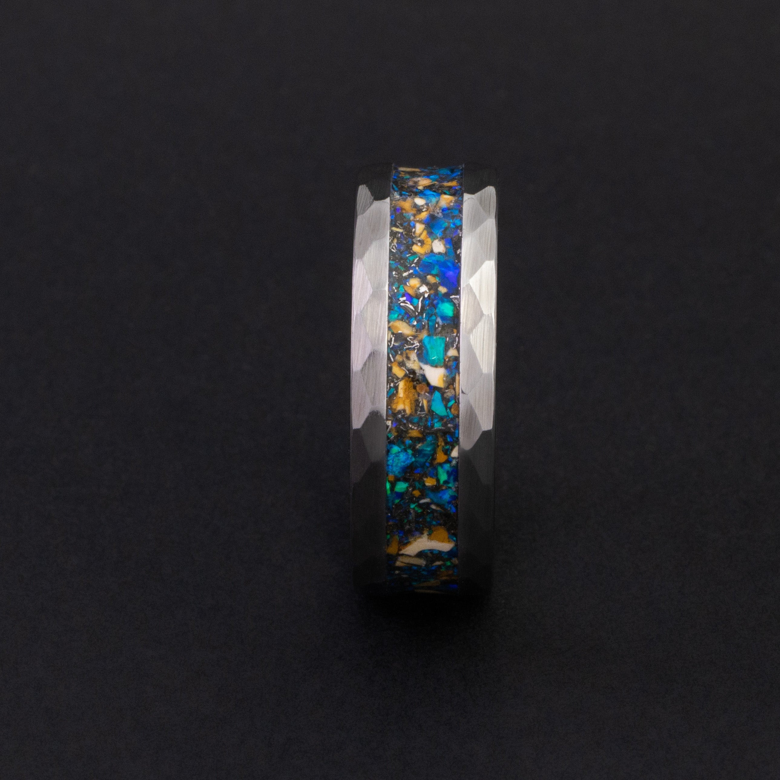 Close up of genuine Velociraptor fossil shards and meteorite in a hammered silver wedding band.