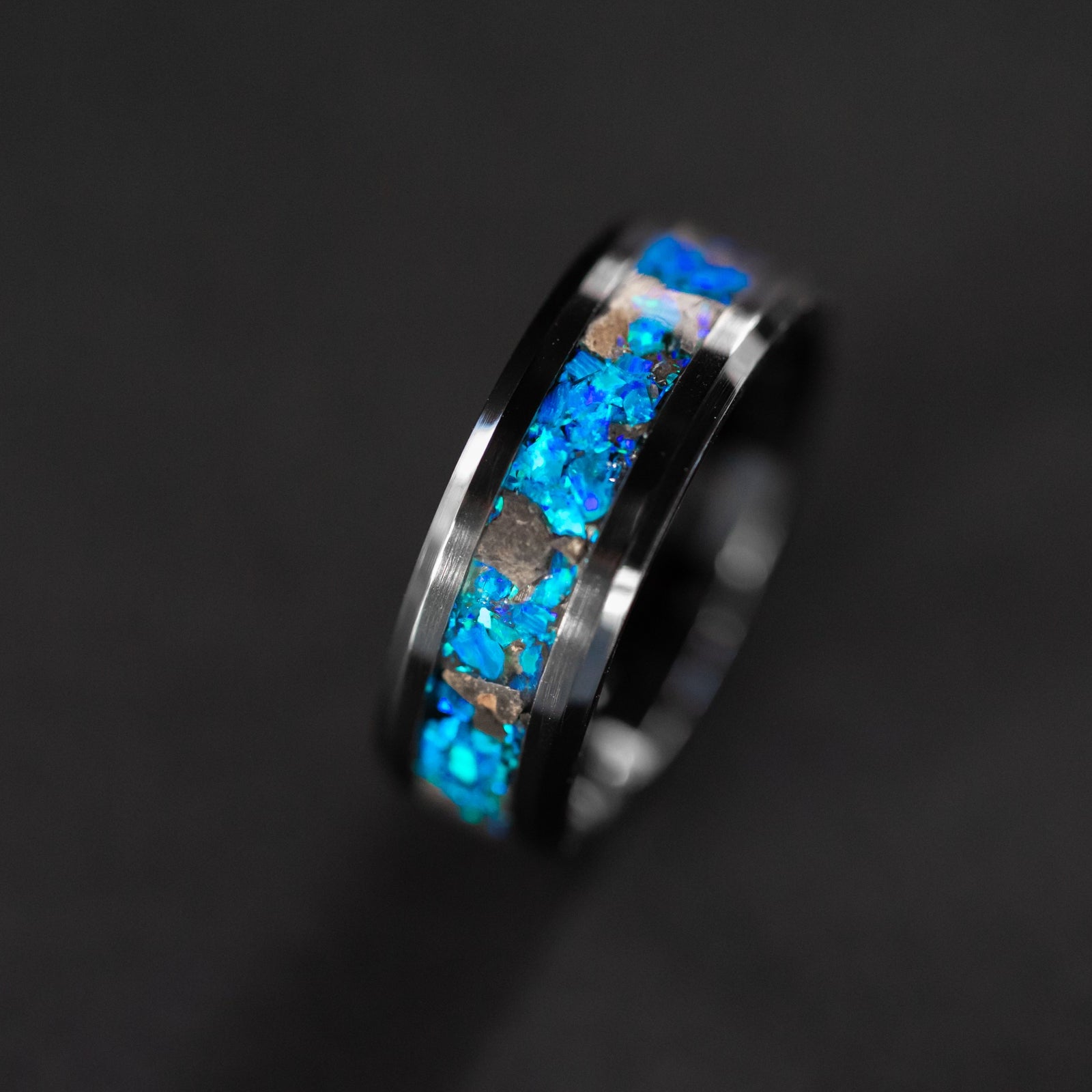 Close up of genuine lunar meteorite pieces surrounded by premium blue opal inlay on beveled black ceramic ring