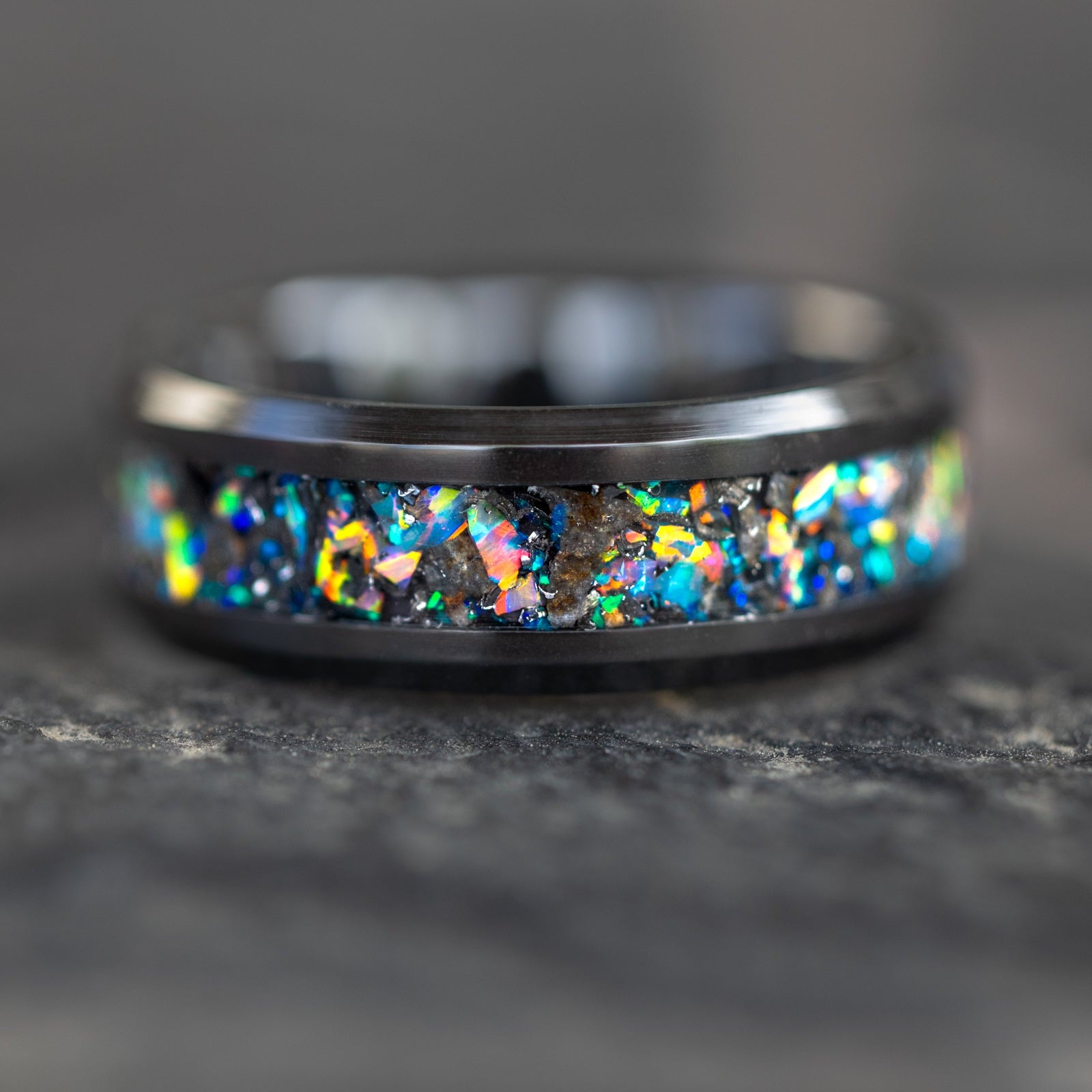 Detail shot of the Lunar Relic Ceramic ring showing authentic lunar meteorite fragments catching light through rainbow moonstone opal inlay on black ceramic band