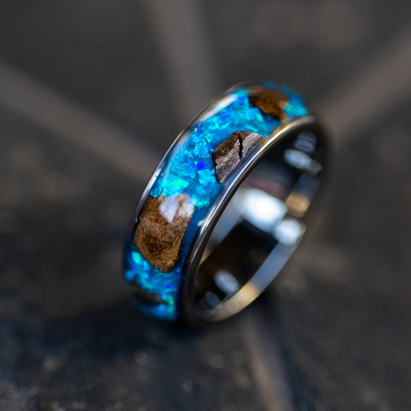 Handcrafted 8mm wide channel tungsten mens wedding band with large authentic T-Rex bone and lunar meteorite pieces in blue opal blue glow inlay made in California