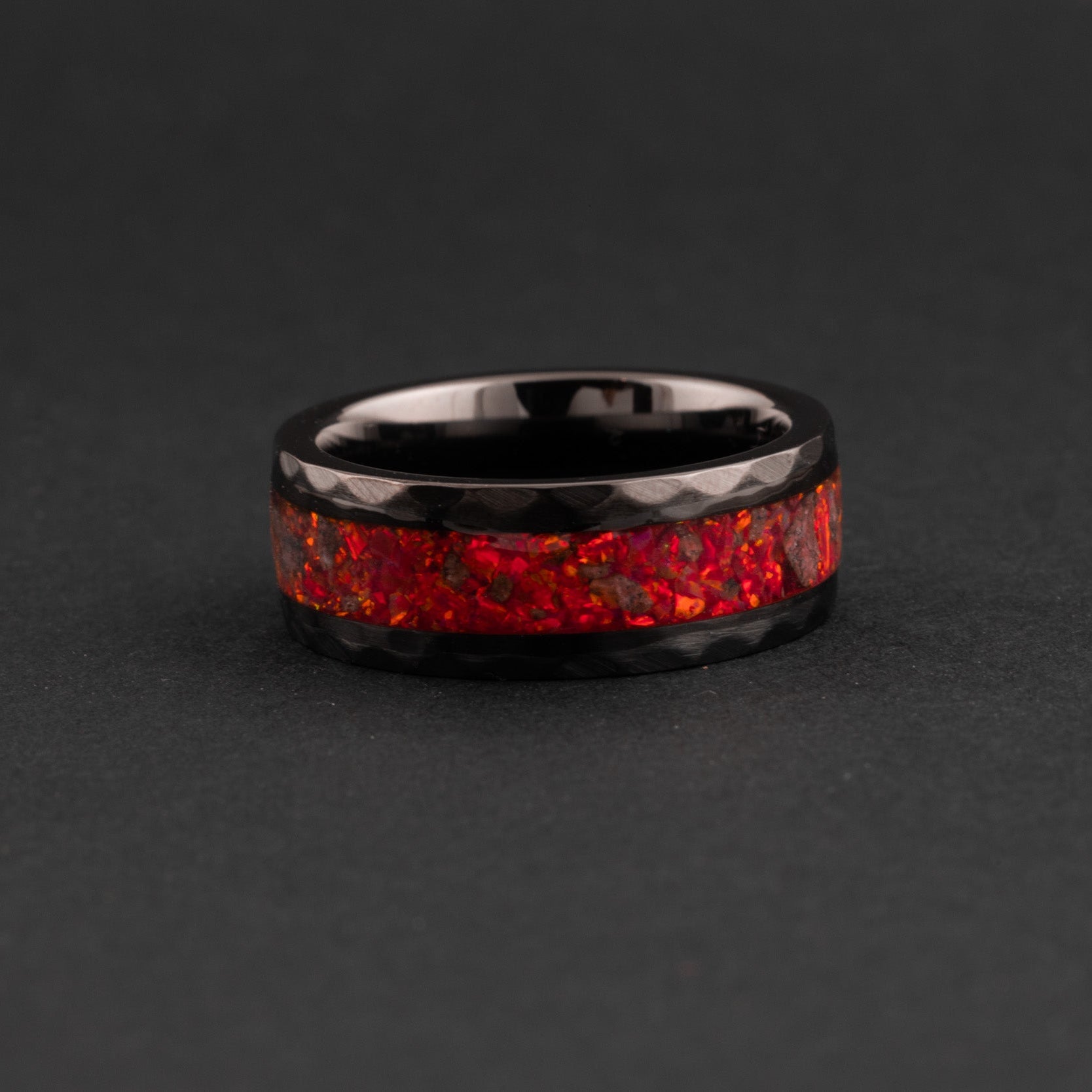 Close up of genuine Mars meteorite fragments and glowing red opal in a hammered ring